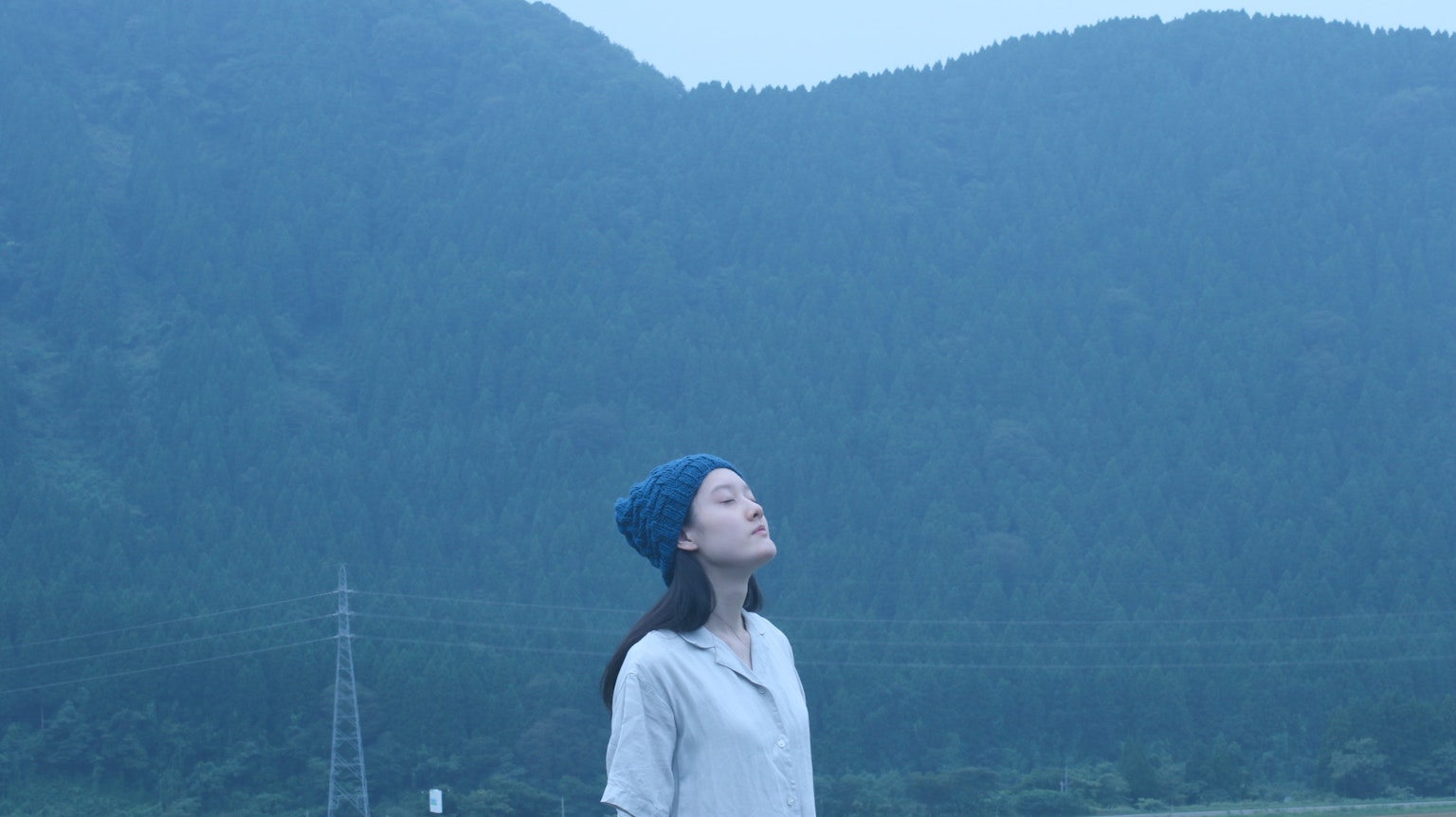 女性在藍色山脈前仰望天空