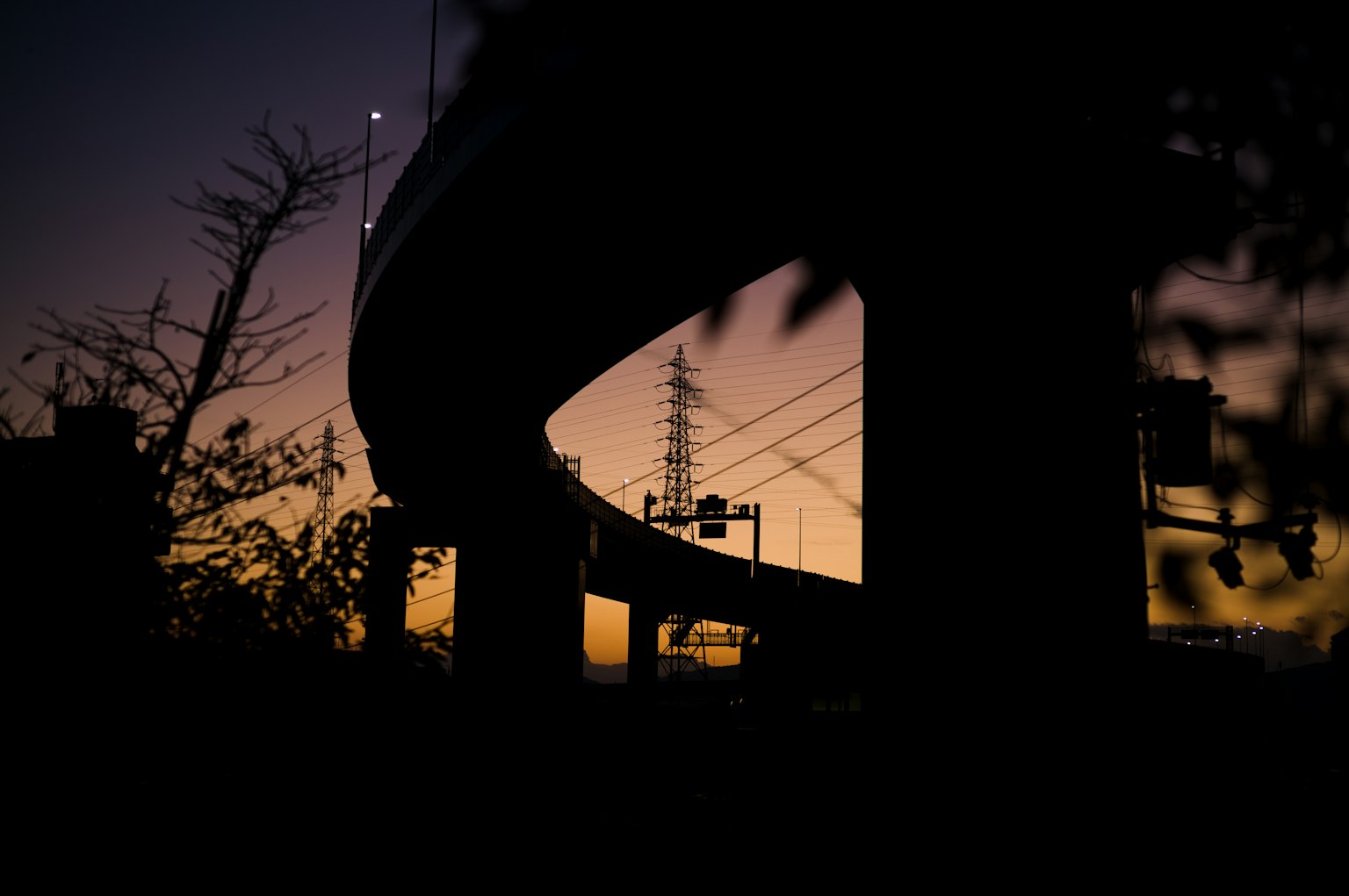 Gebogene Überführung silhouettiert gegen einen Sonnenuntergang mit Bäumen