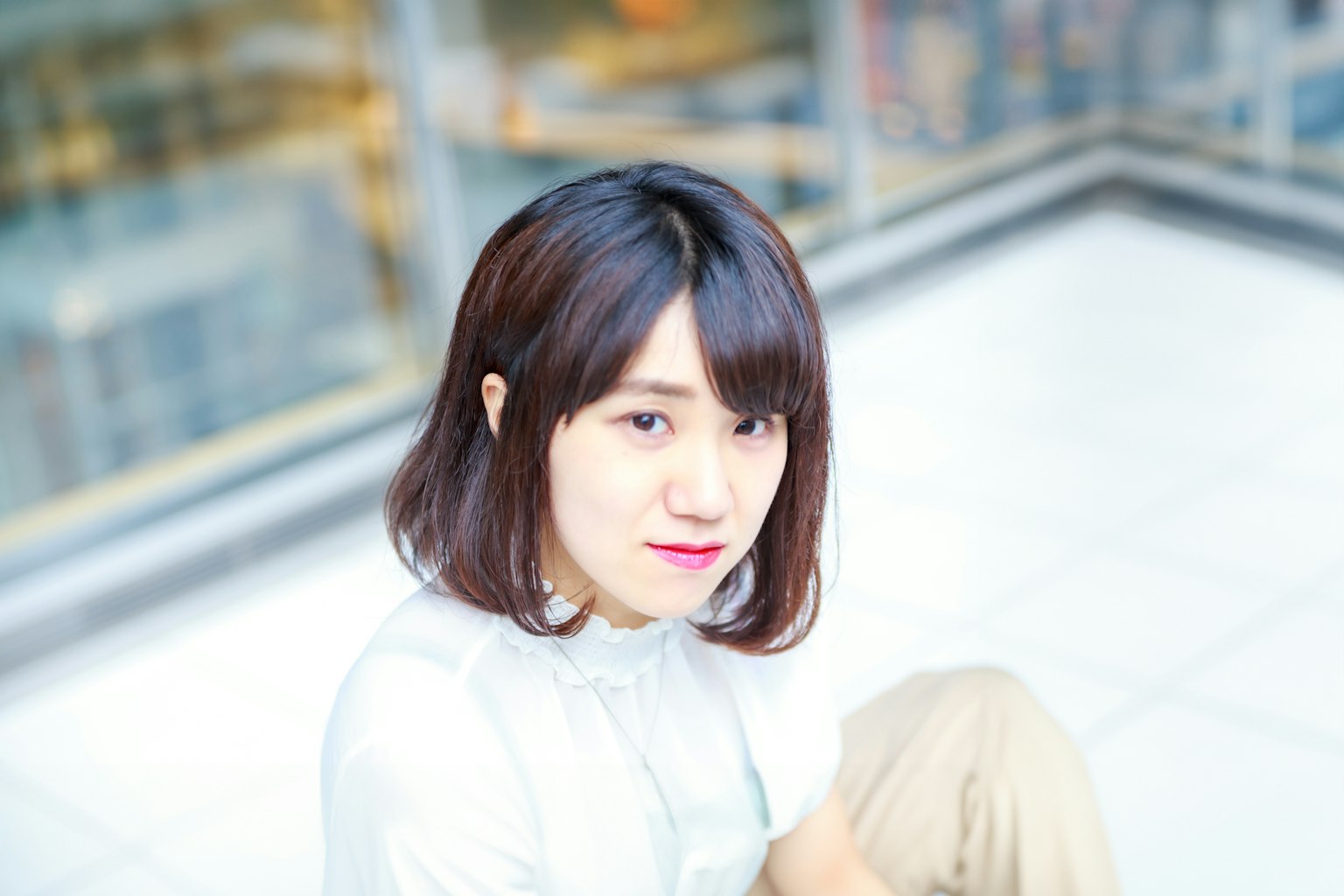 在明亮背景下微笑的女性肖像，肩长柔软的头发，穿着白色上衣