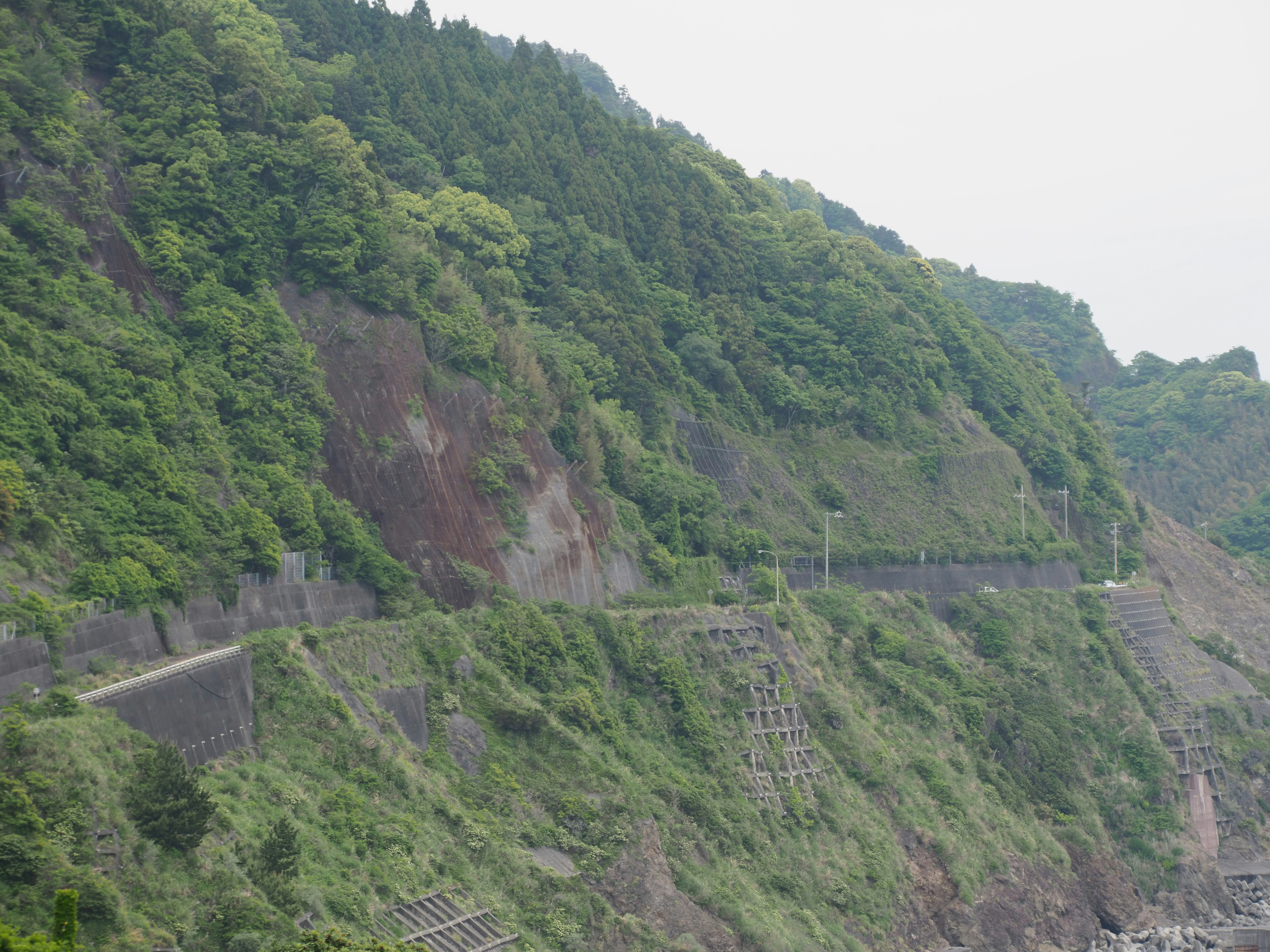 緑の山肌に沿う斜面の法面と防災設備