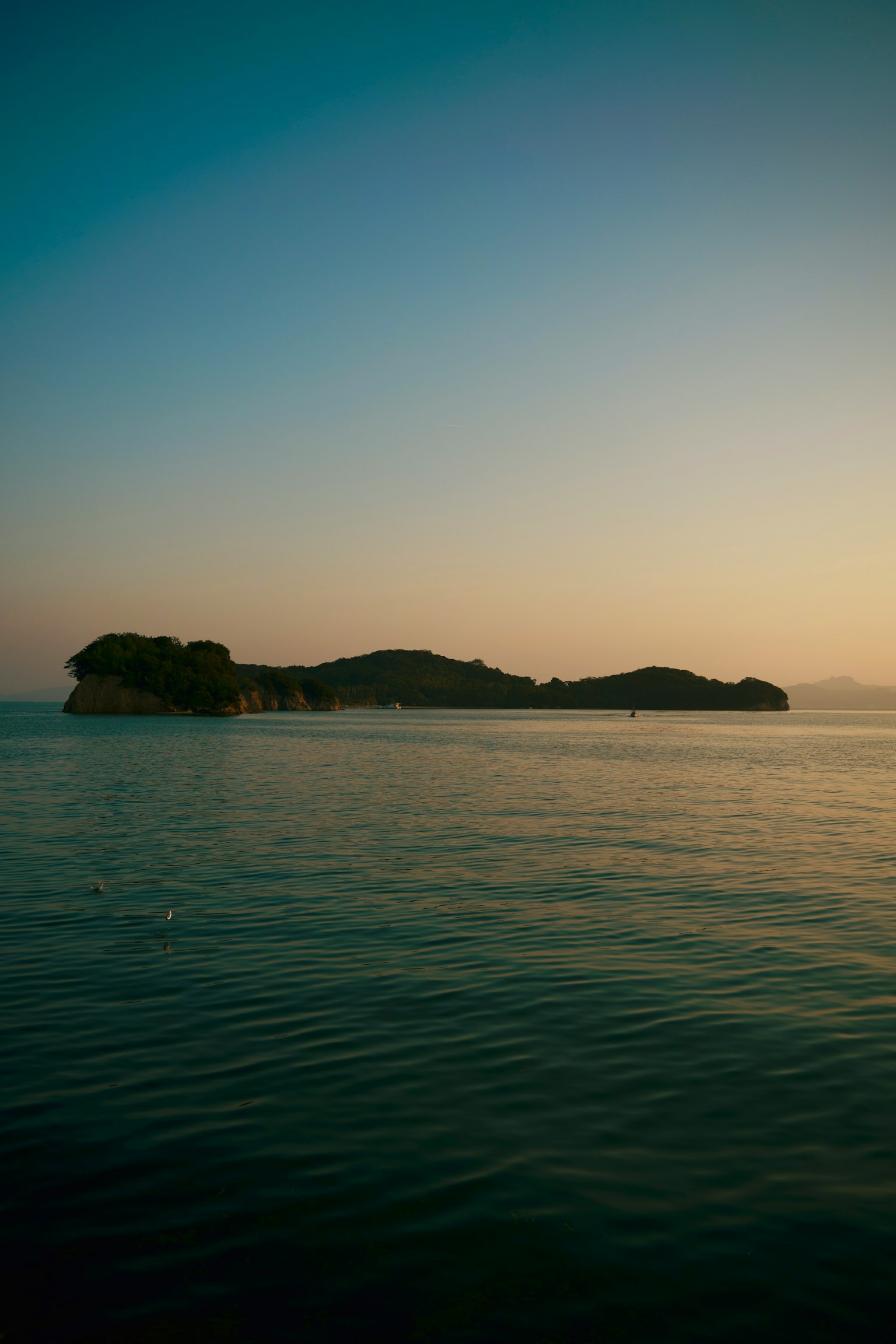 Vista serena dell'oceano con la silhouette di un'isola isolata durante un bellissimo tramonto