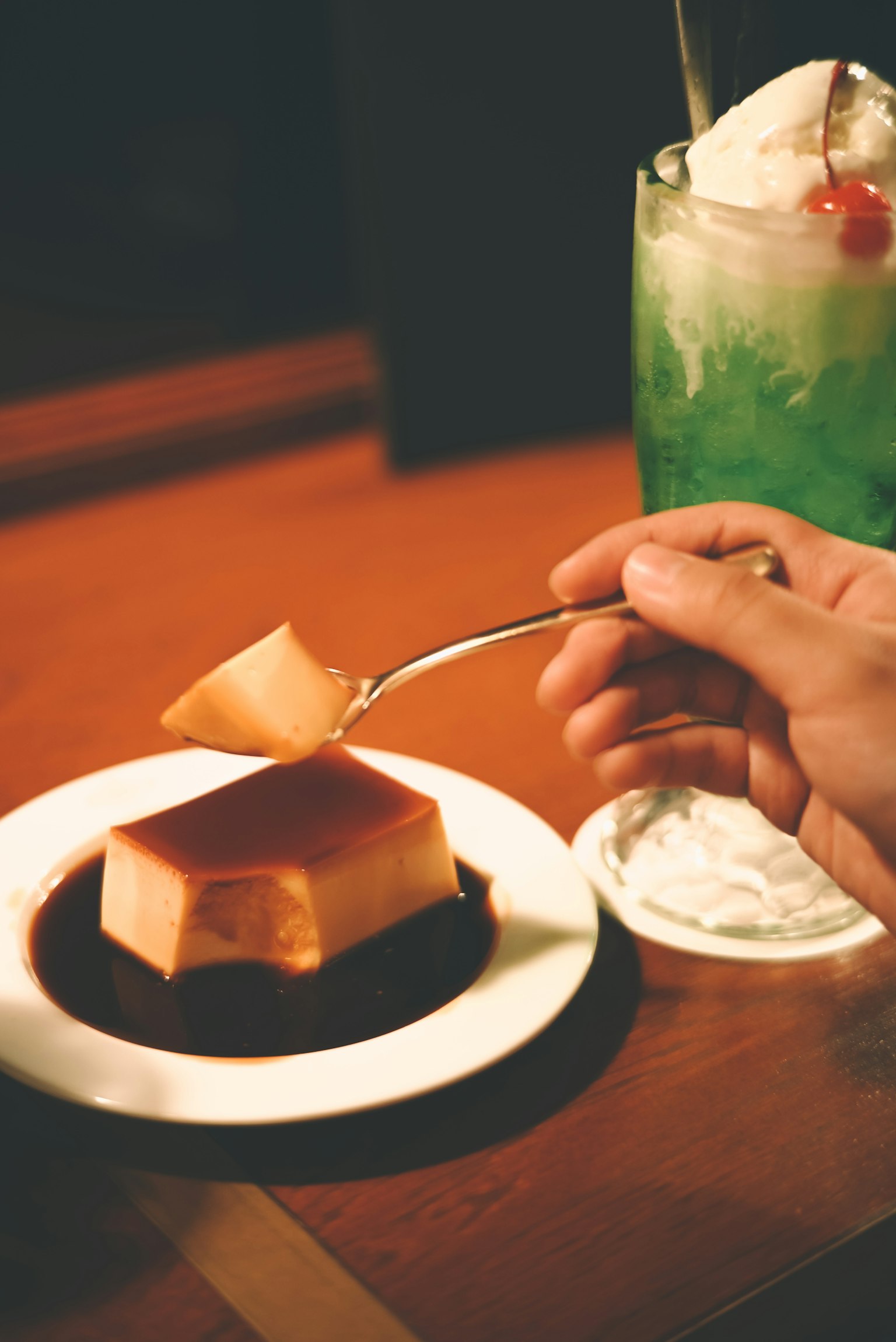 Eine Person mit einem Löffel ist dabei, Flan mit Karamellsauce zu essen