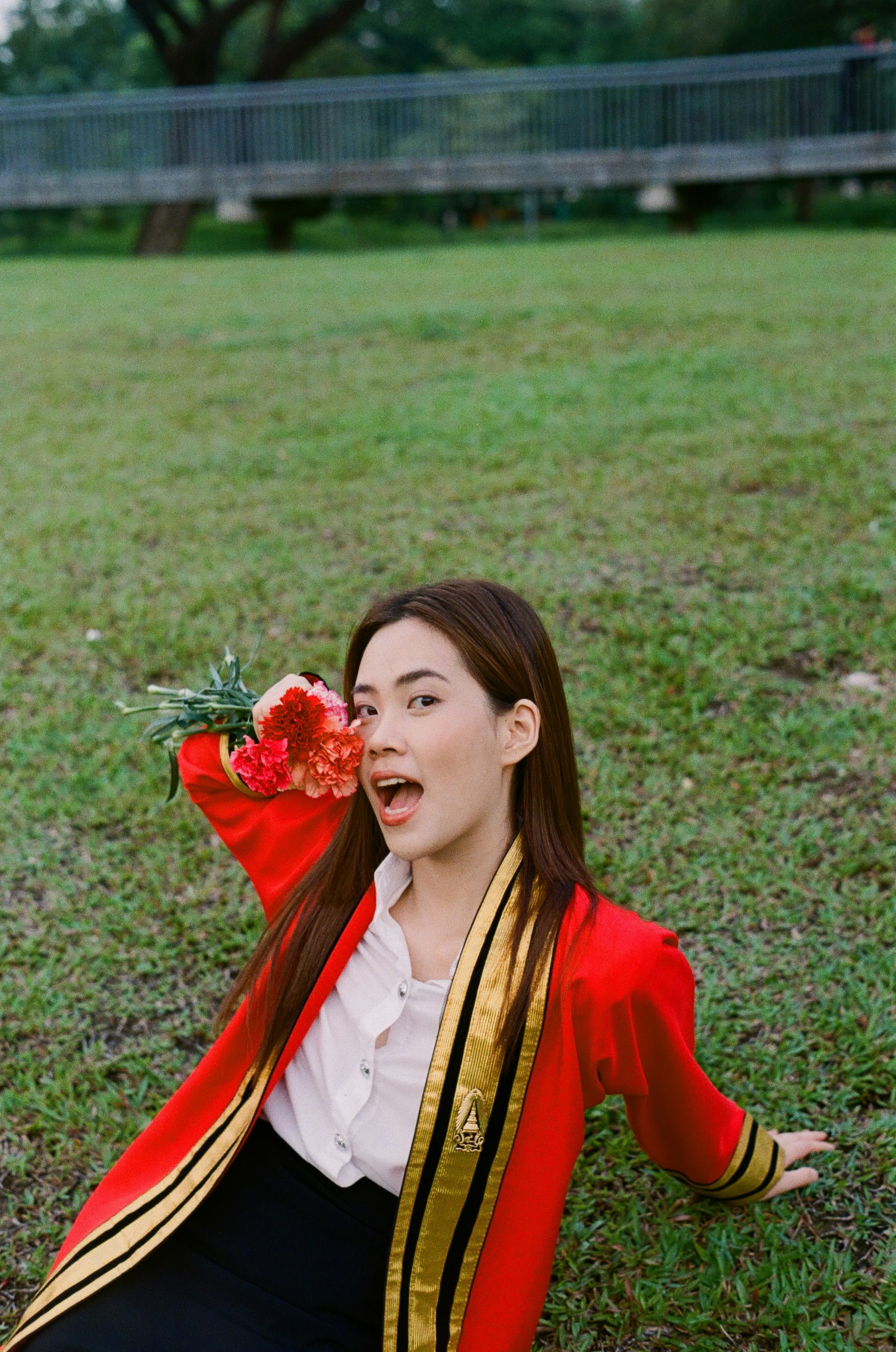 草地上手捧花束的畢業女性