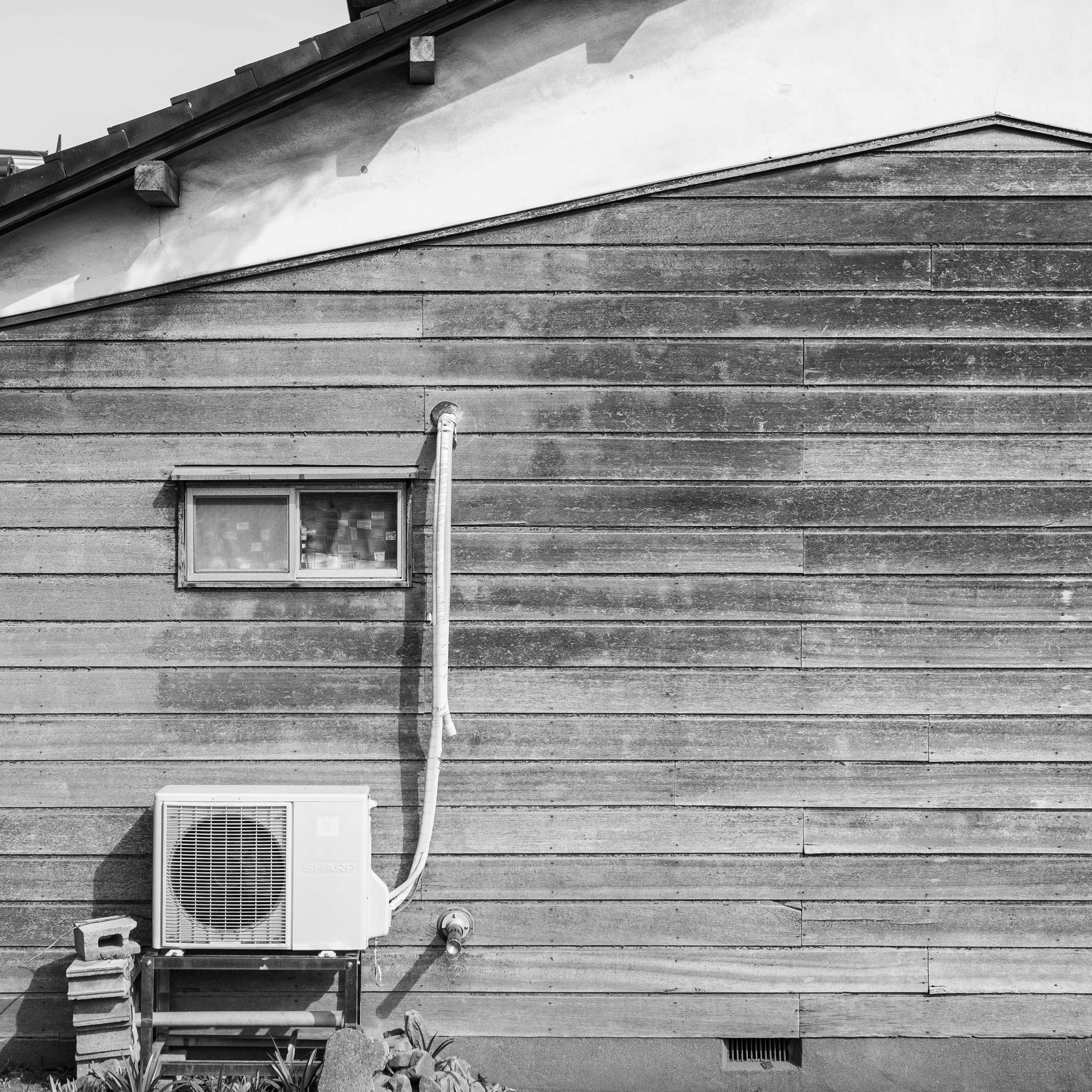 Building exterior with a wall-mounted outdoor AC unit and piping