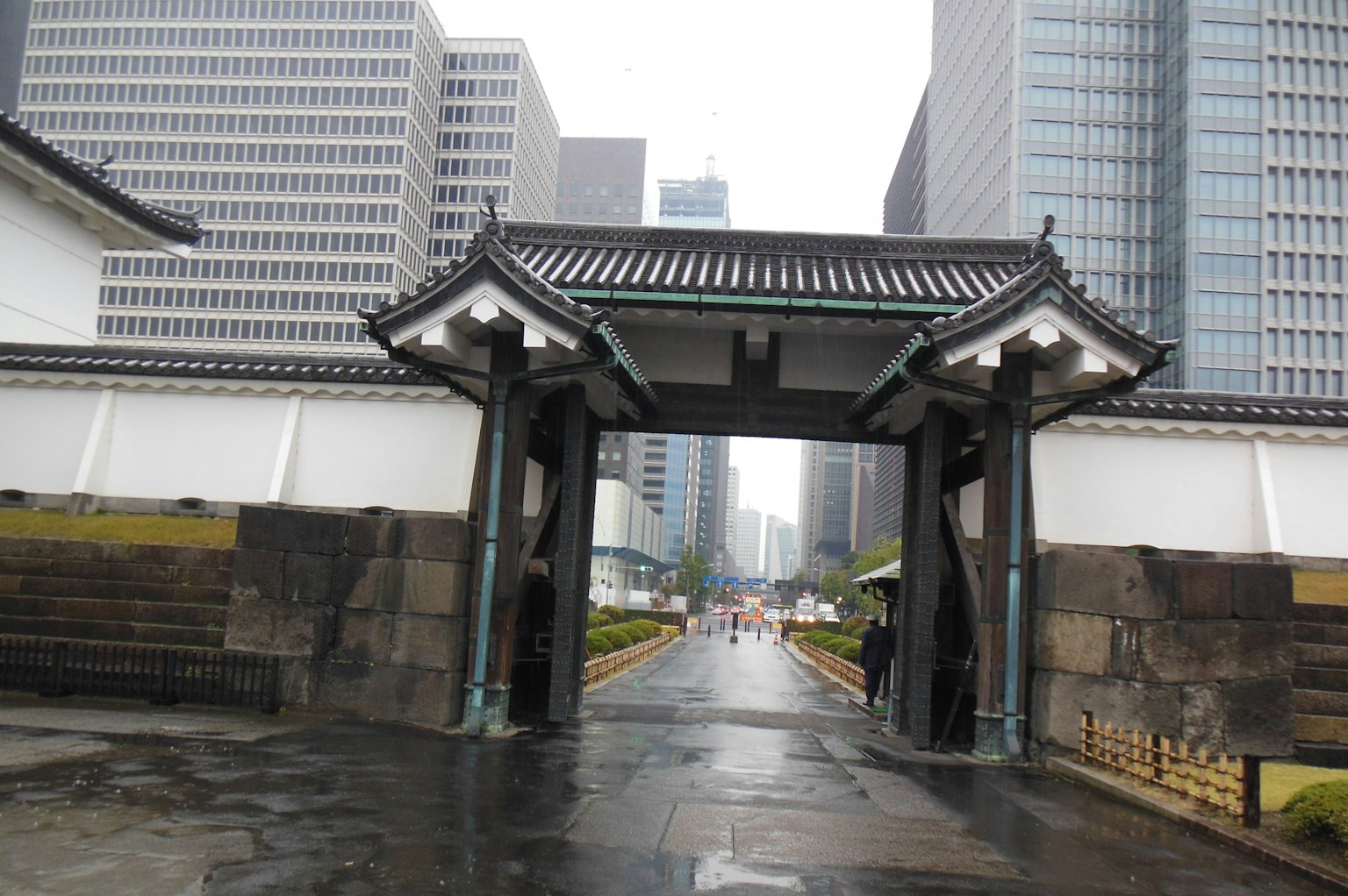 Tokyo Imperial Palace gate with modern skyscrapers in the background during rain