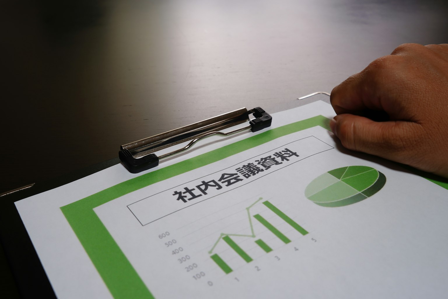 Une main reposant sur un document avec des graphiques et un diagramme circulaire