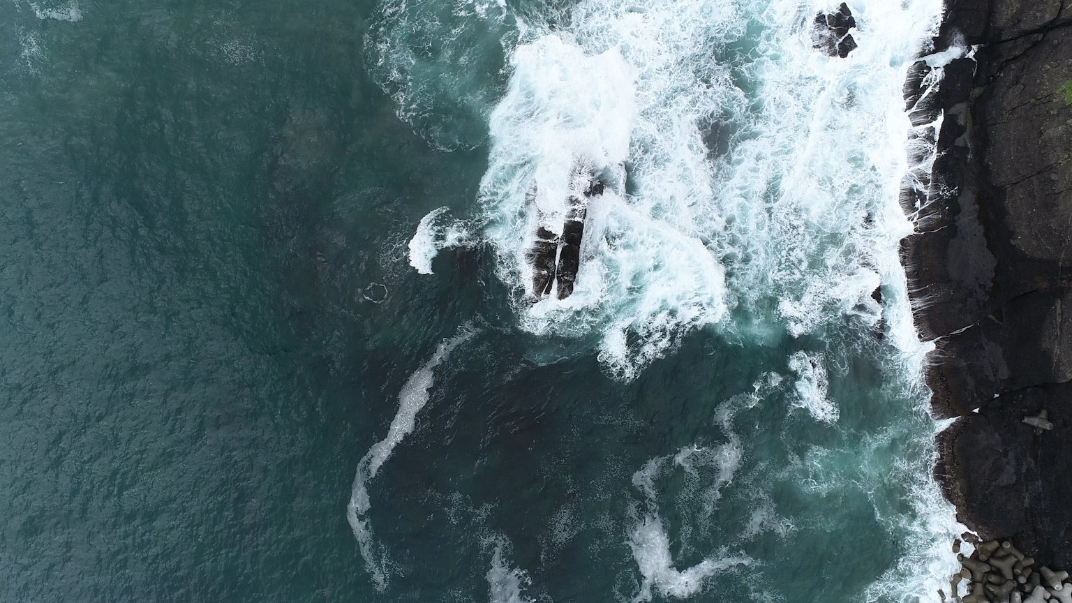 Vista aérea de las olas del océano rompiendo contra las rocas