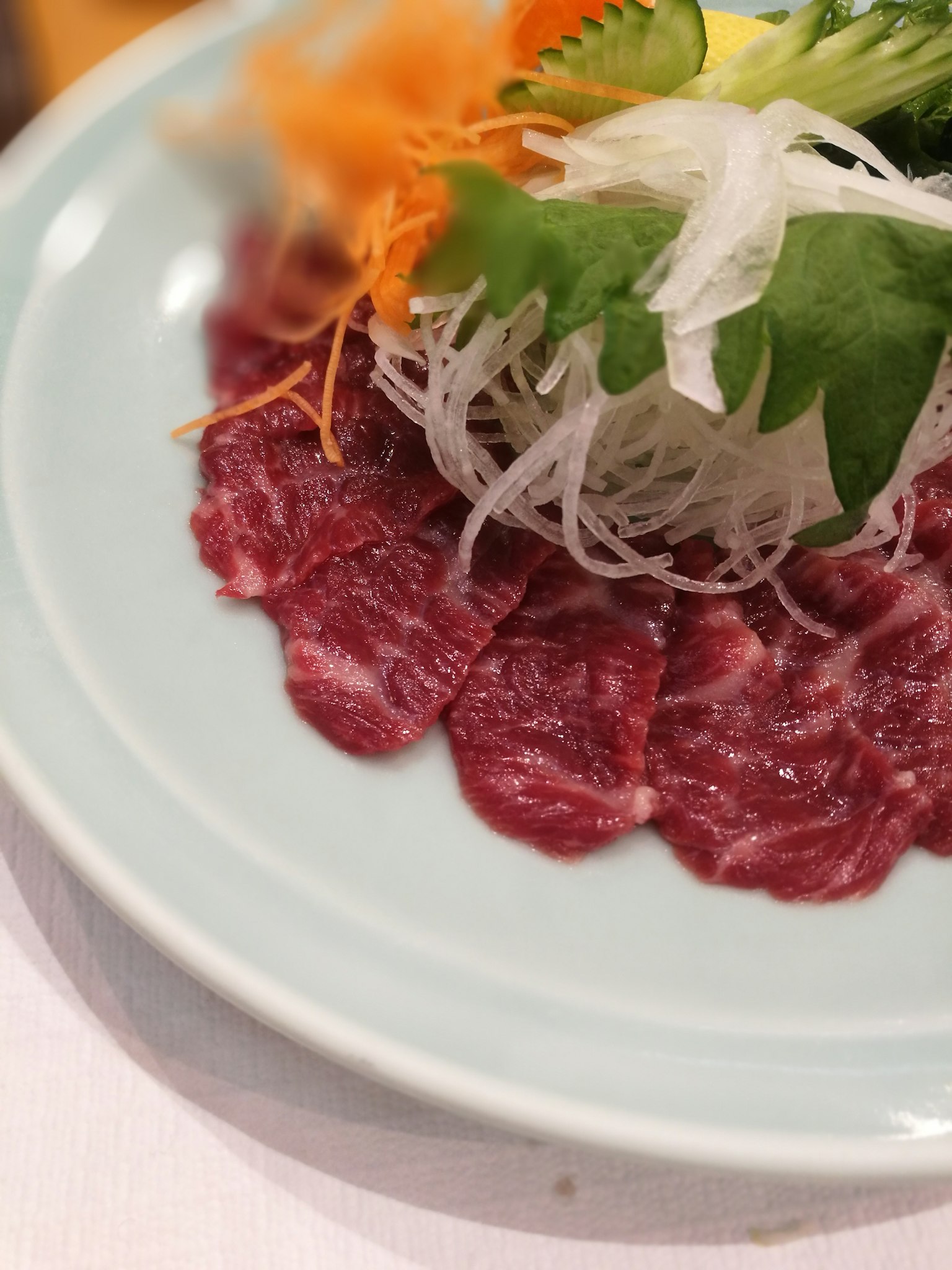 Dünn geschnittenes rohes Fleisch mit frischem Gemüse serviert