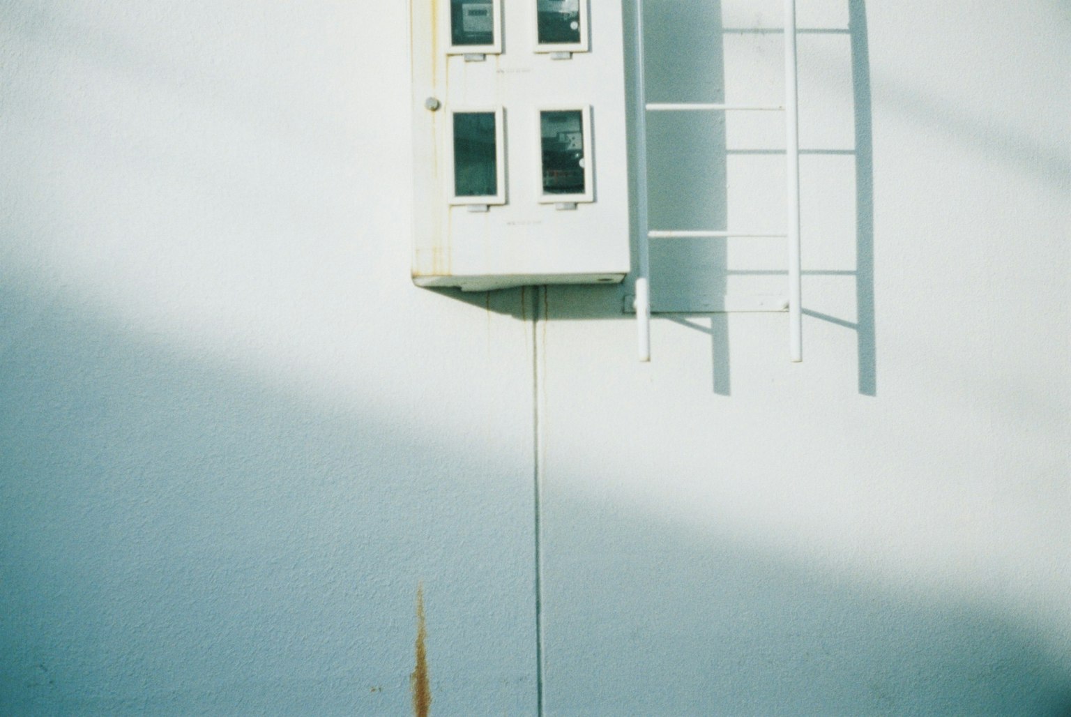 Immagine di una piccola porta montata su un muro bianco con una scala