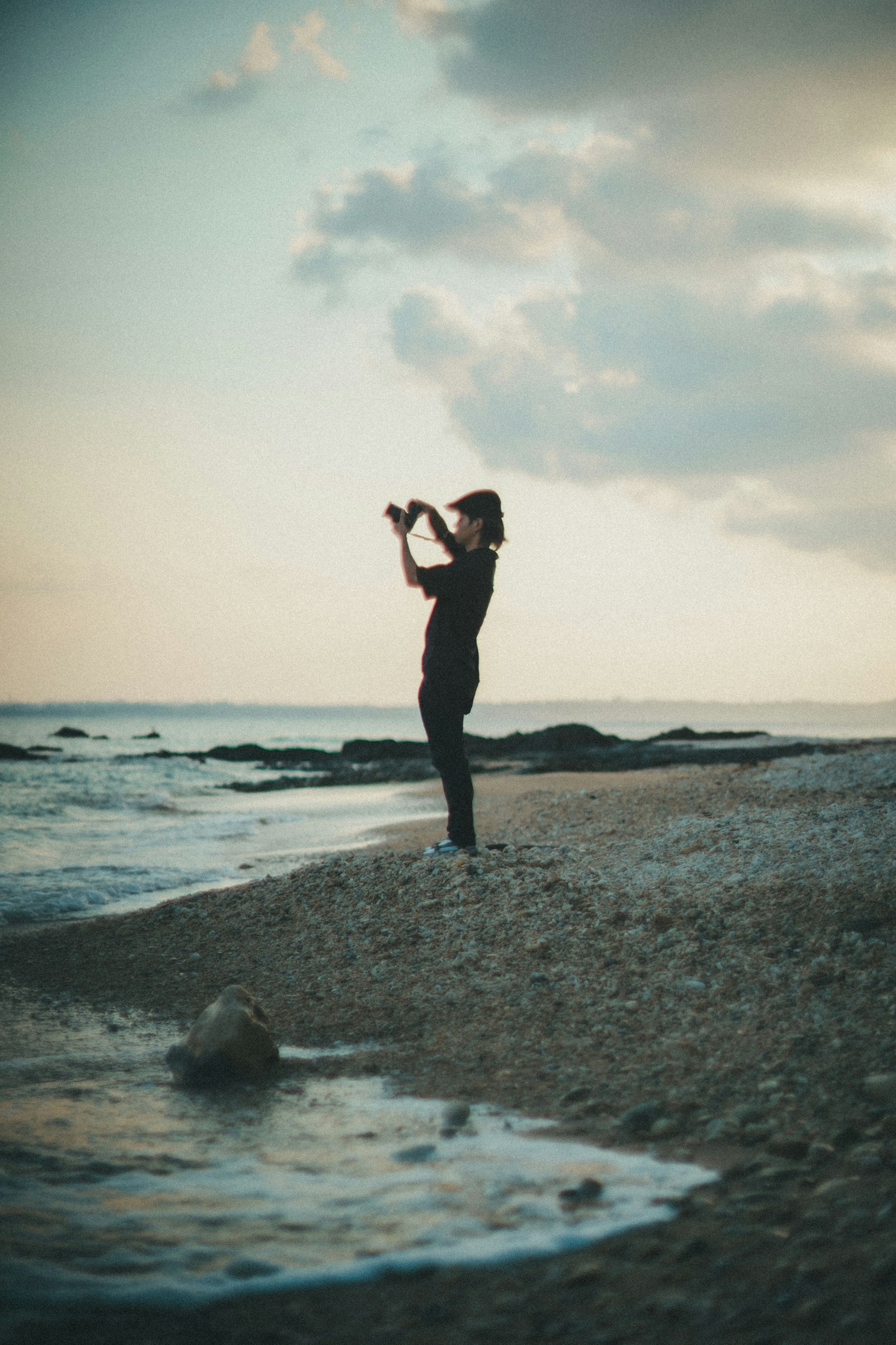 Persona tomando fotos en la playa con un cielo de atardecer tranquilo