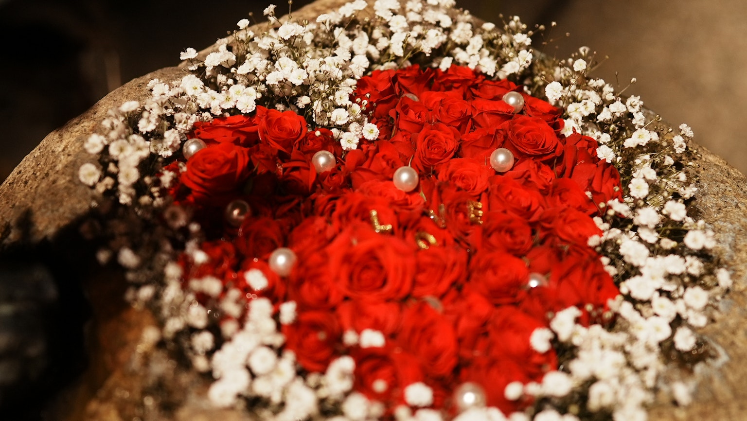 Herzförmige Anordnung von roten Rosen und weißen Blumen