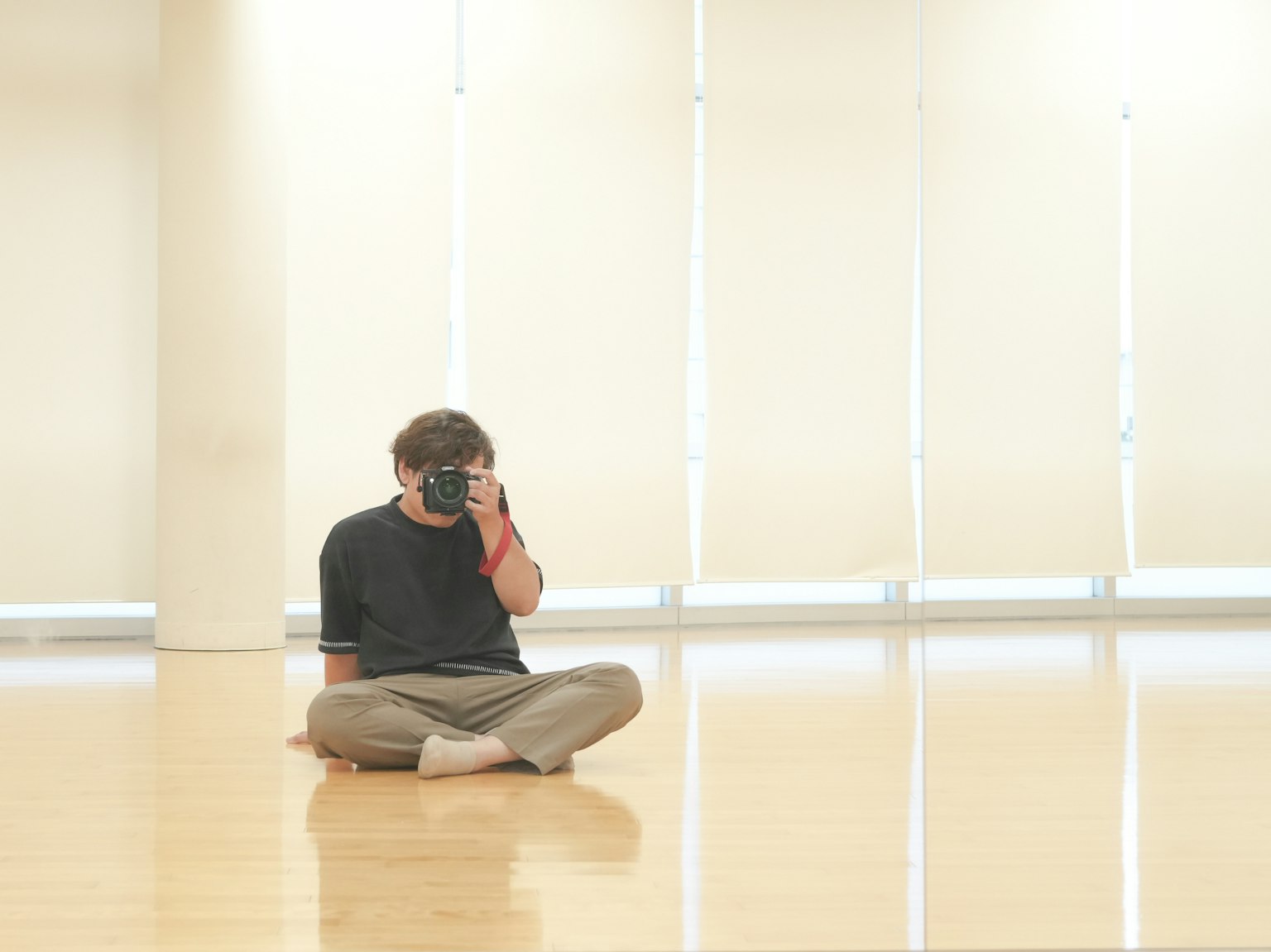 Jeune homme assis sur le sol tenant un appareil photo dans un studio lumineux