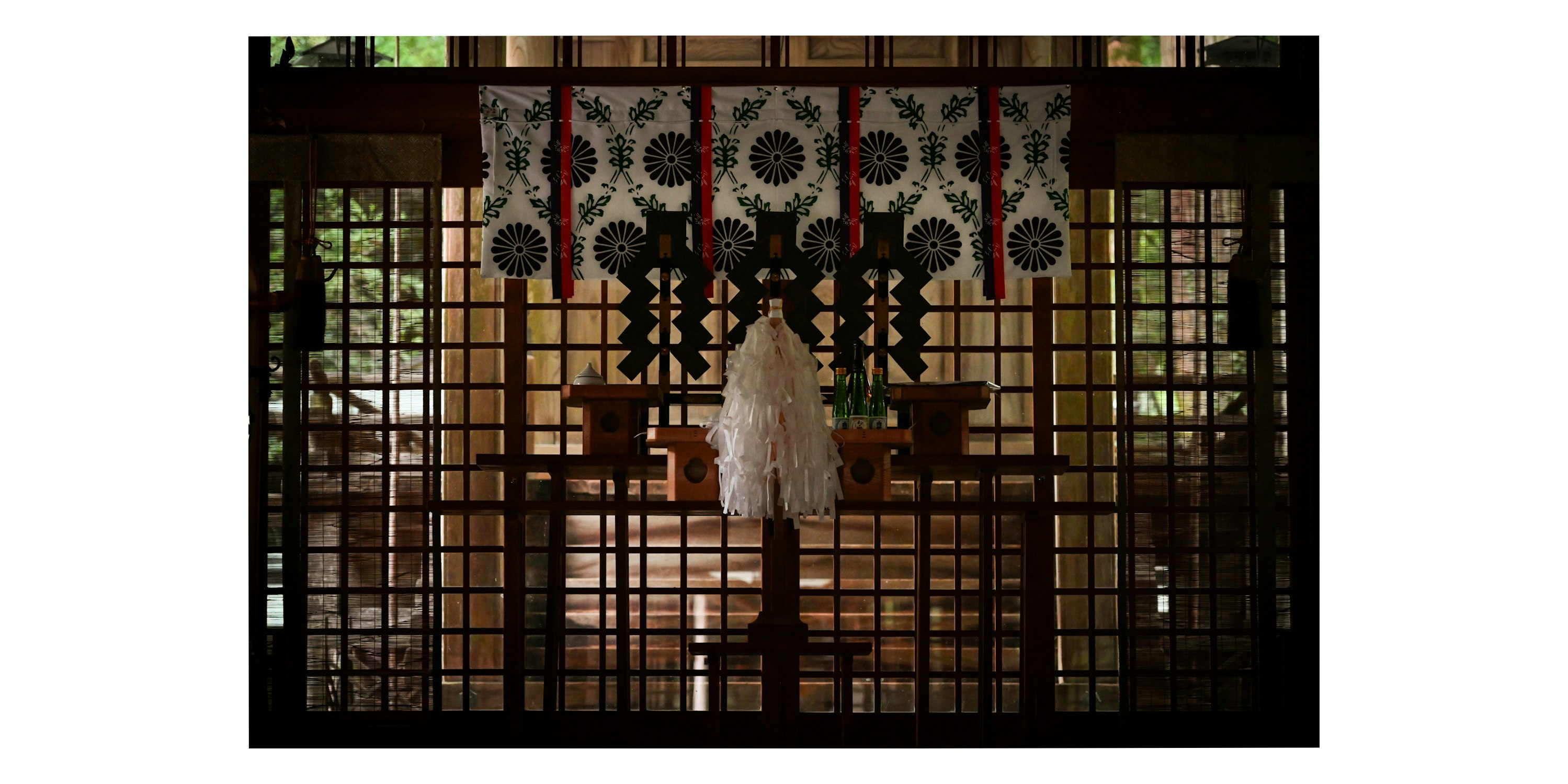 a person in a white dress standing beyond a lattice gate