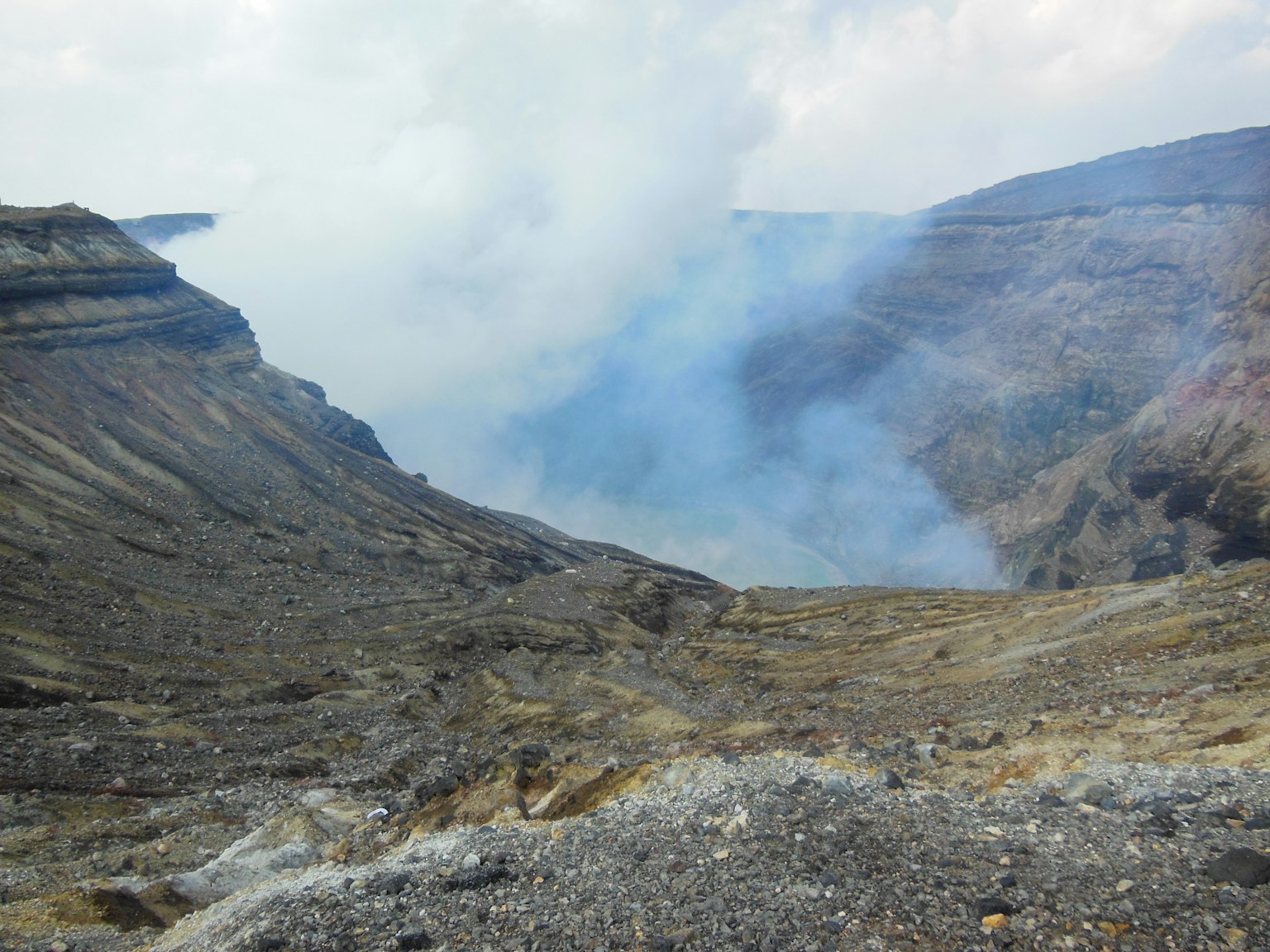 Volcanic crater landscape with rising smoke and rugged terrain