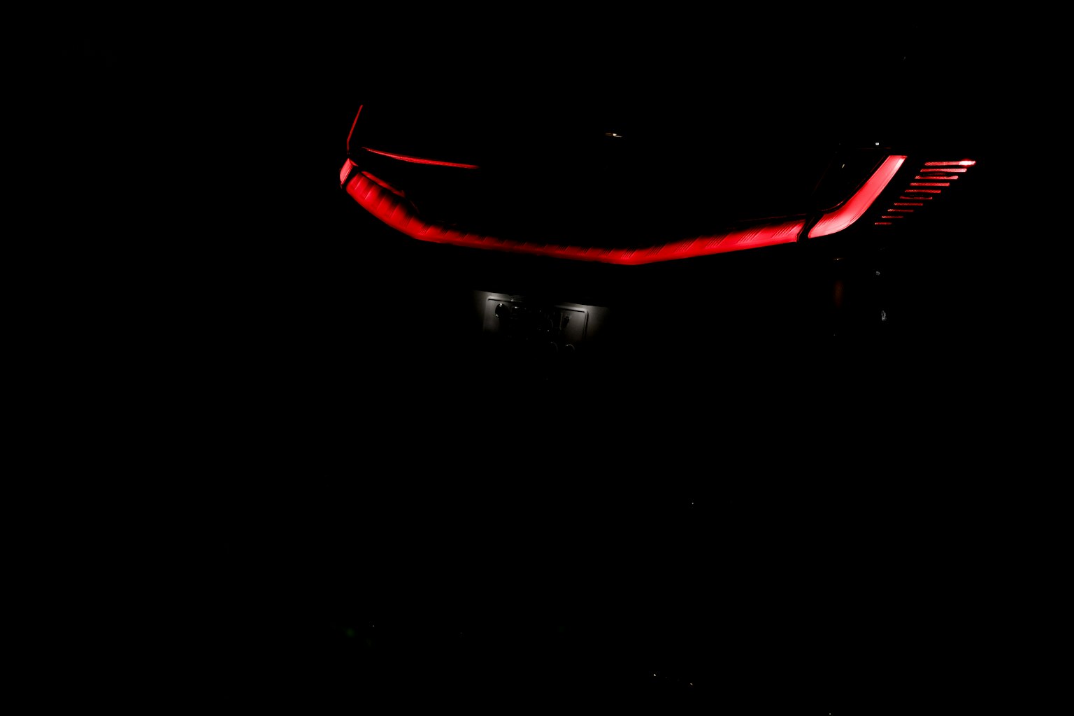 Car front with red lights against a dark background