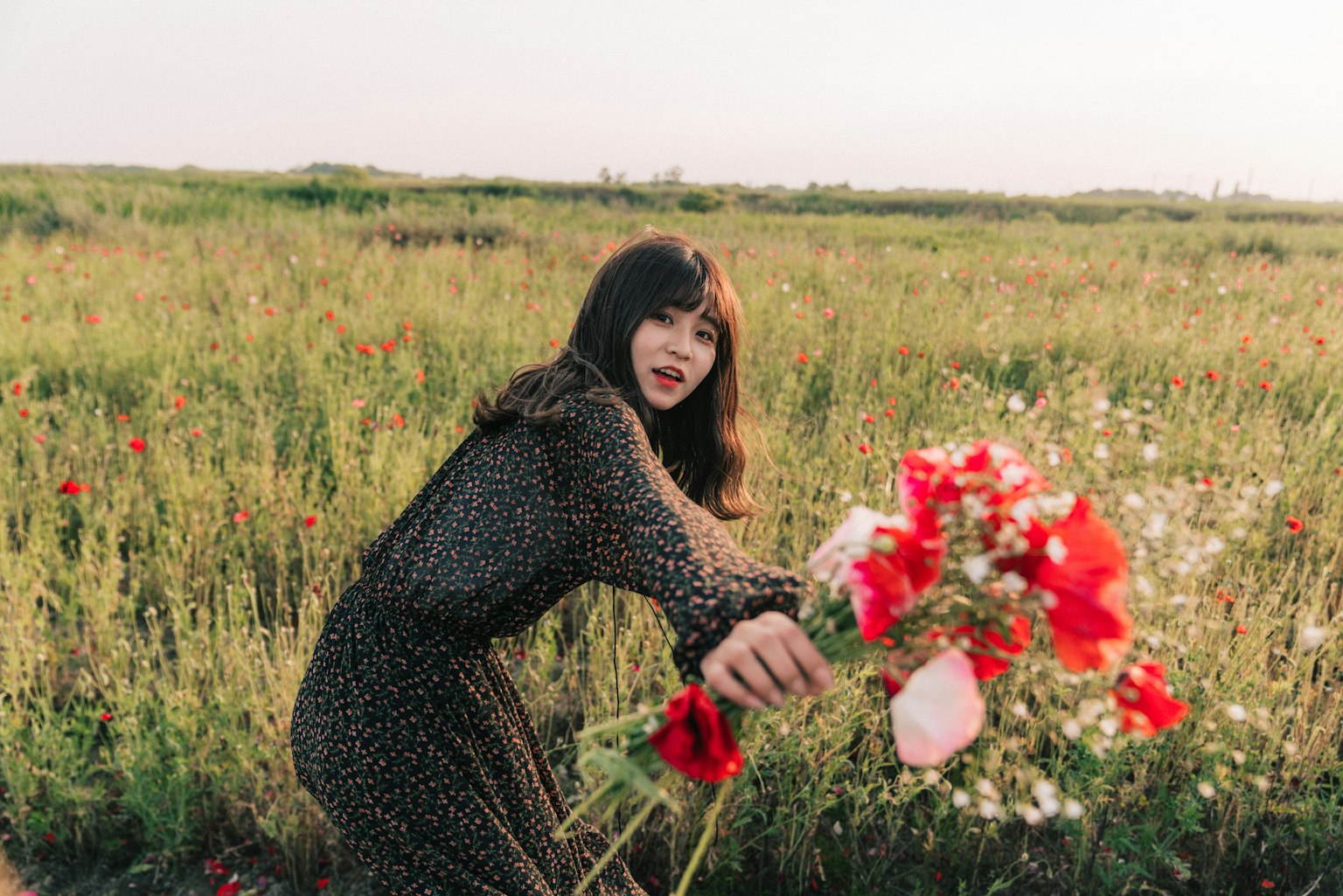 Donna con un bouquet di fiori in un campo erboso