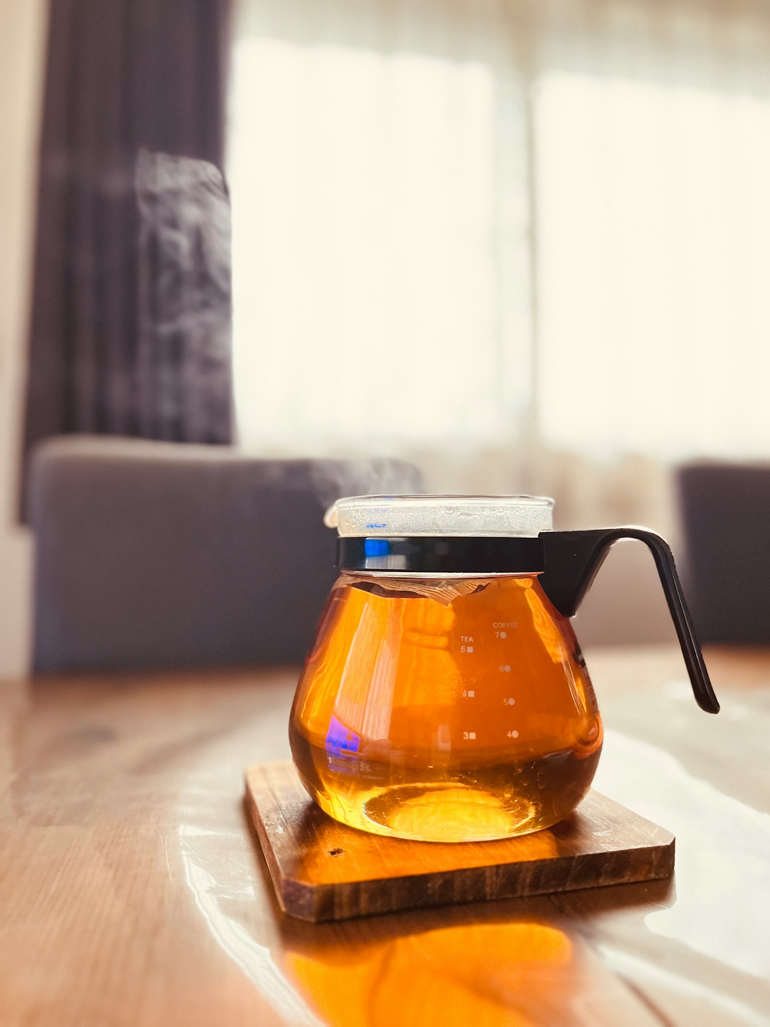 Une théière en verre remplie de thé chaud émettant de la vapeur