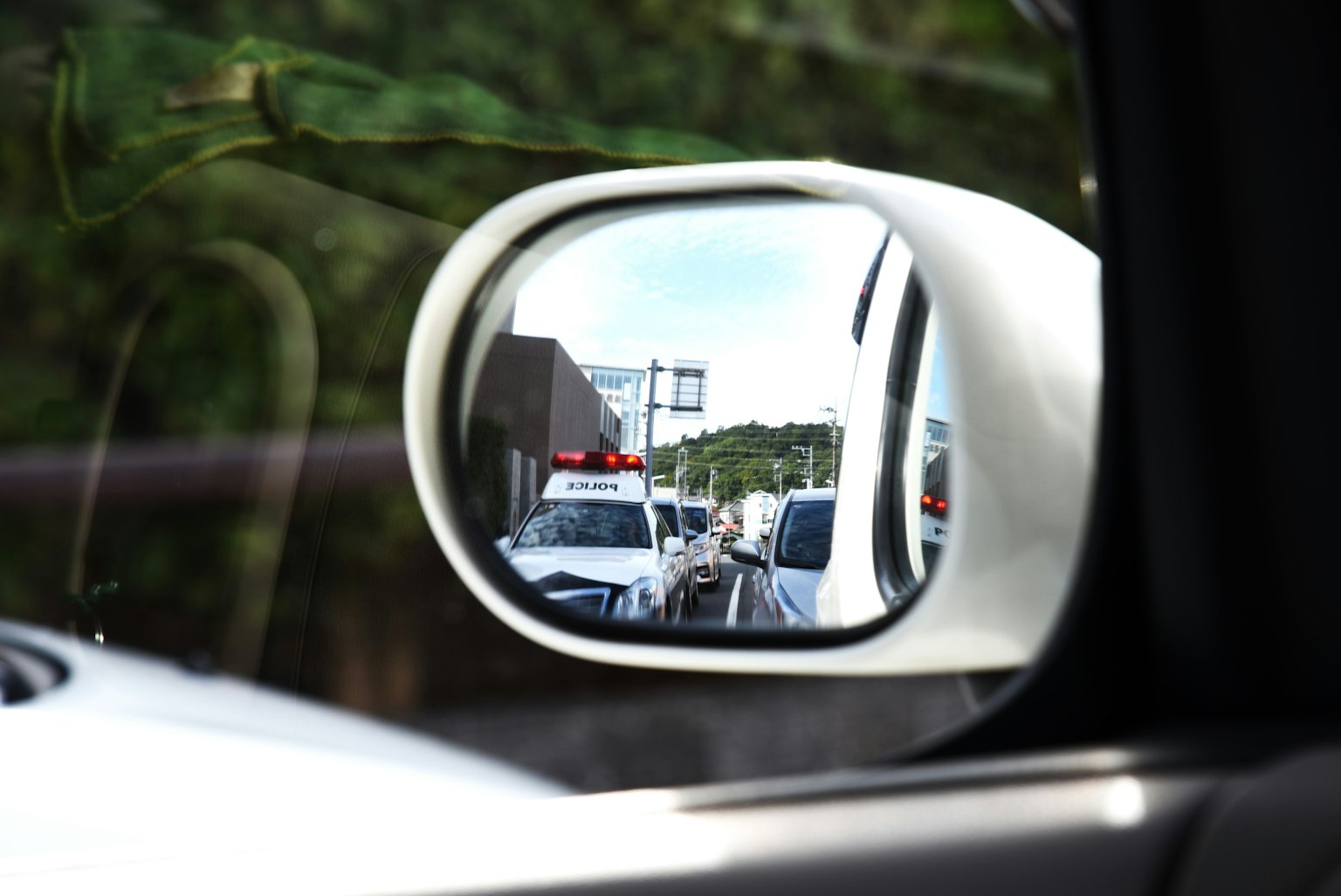 白色車輛側鏡中反射的交通場景和紅色警車