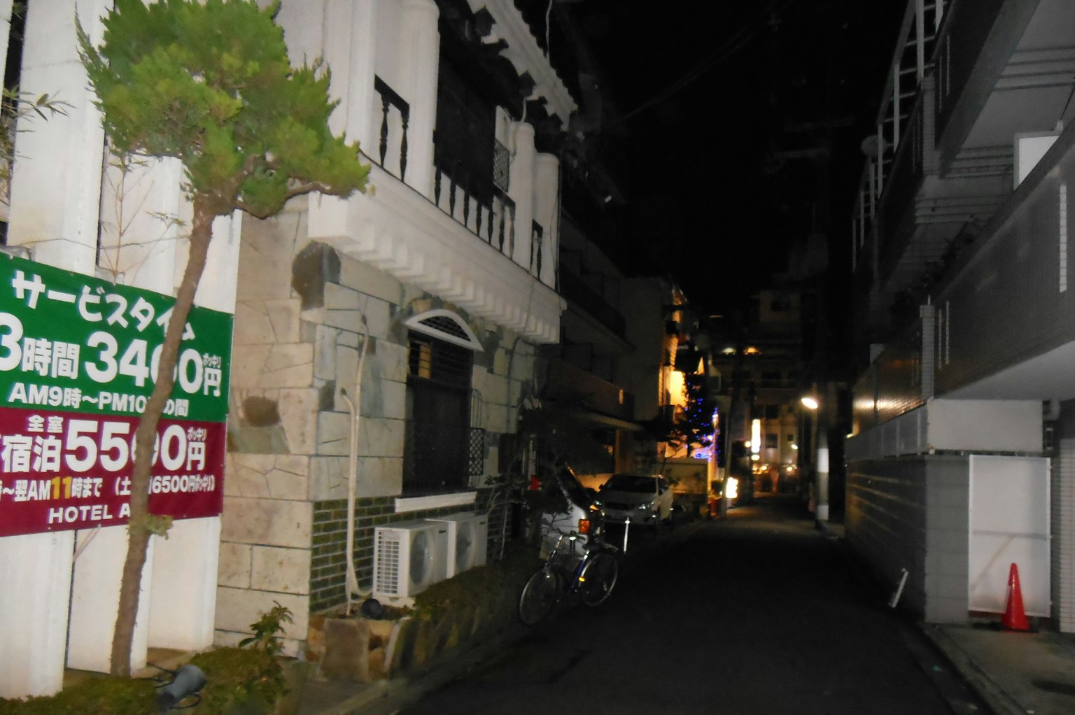 Straßenansicht bei Nacht mit Gebäuden und Beschilderungen
