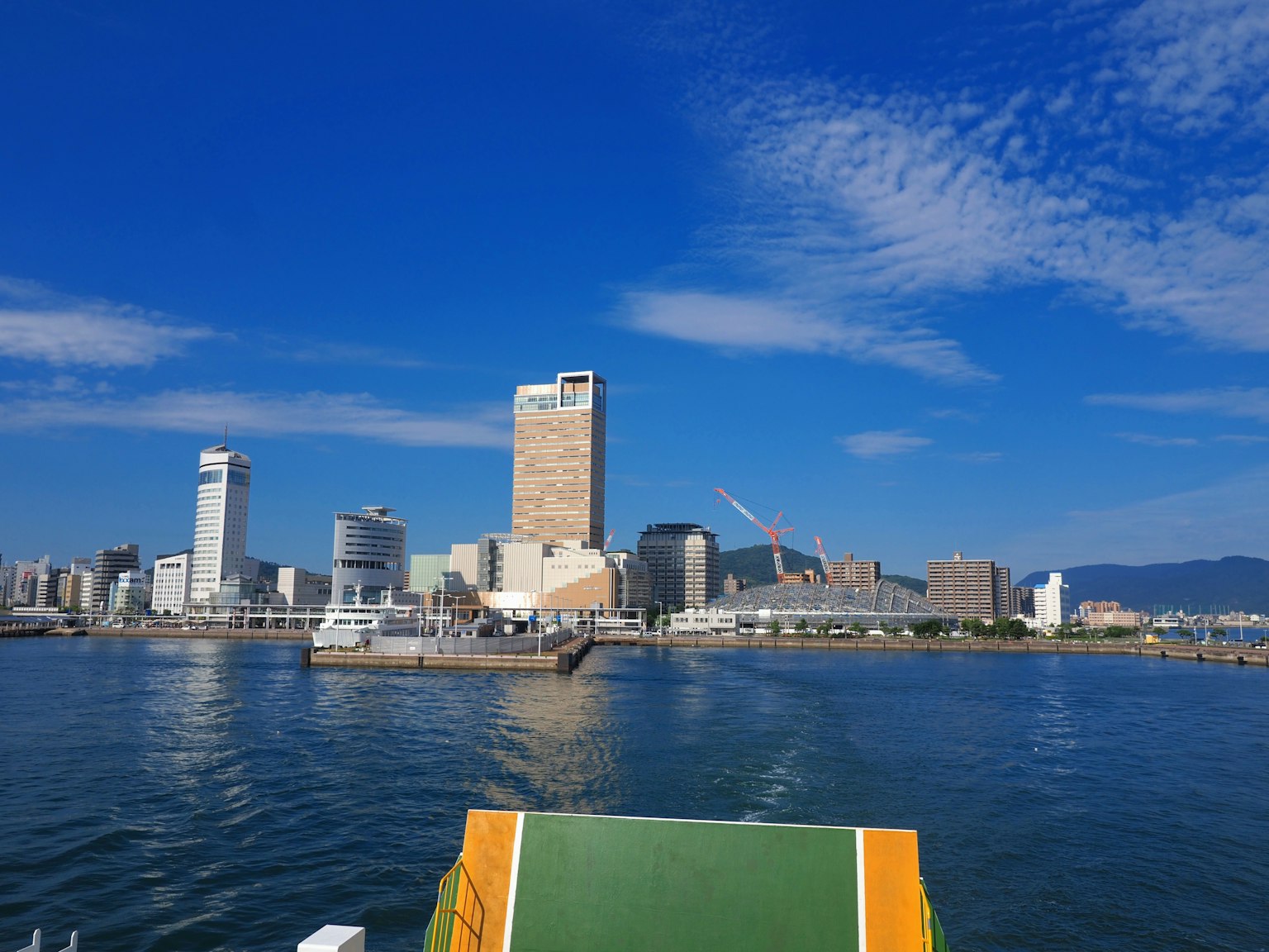 Paesaggio urbano con grattacieli e porto sotto un cielo blu e acqua