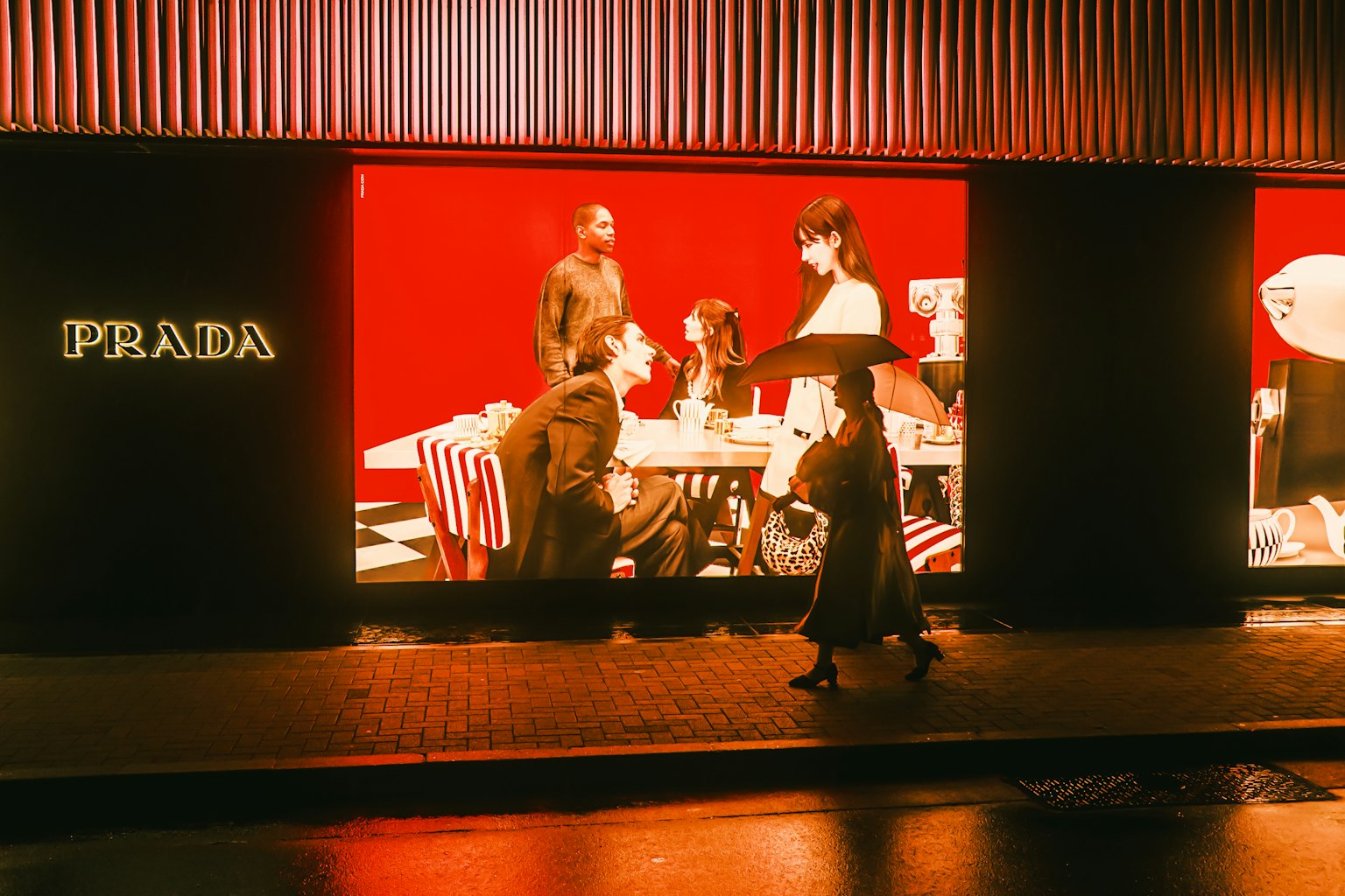 หน้าต่างร้าน Prada แสดงผู้คนและพื้นหลังสีแดง