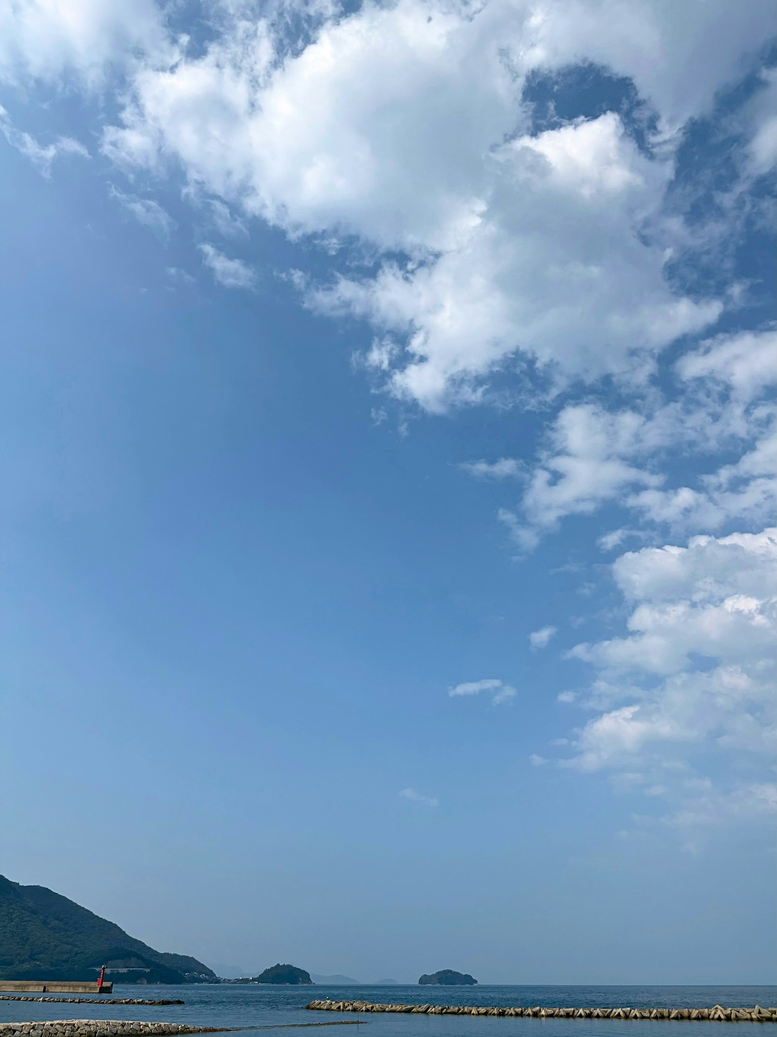 海岸风景蓝天白云小岛和防波堤