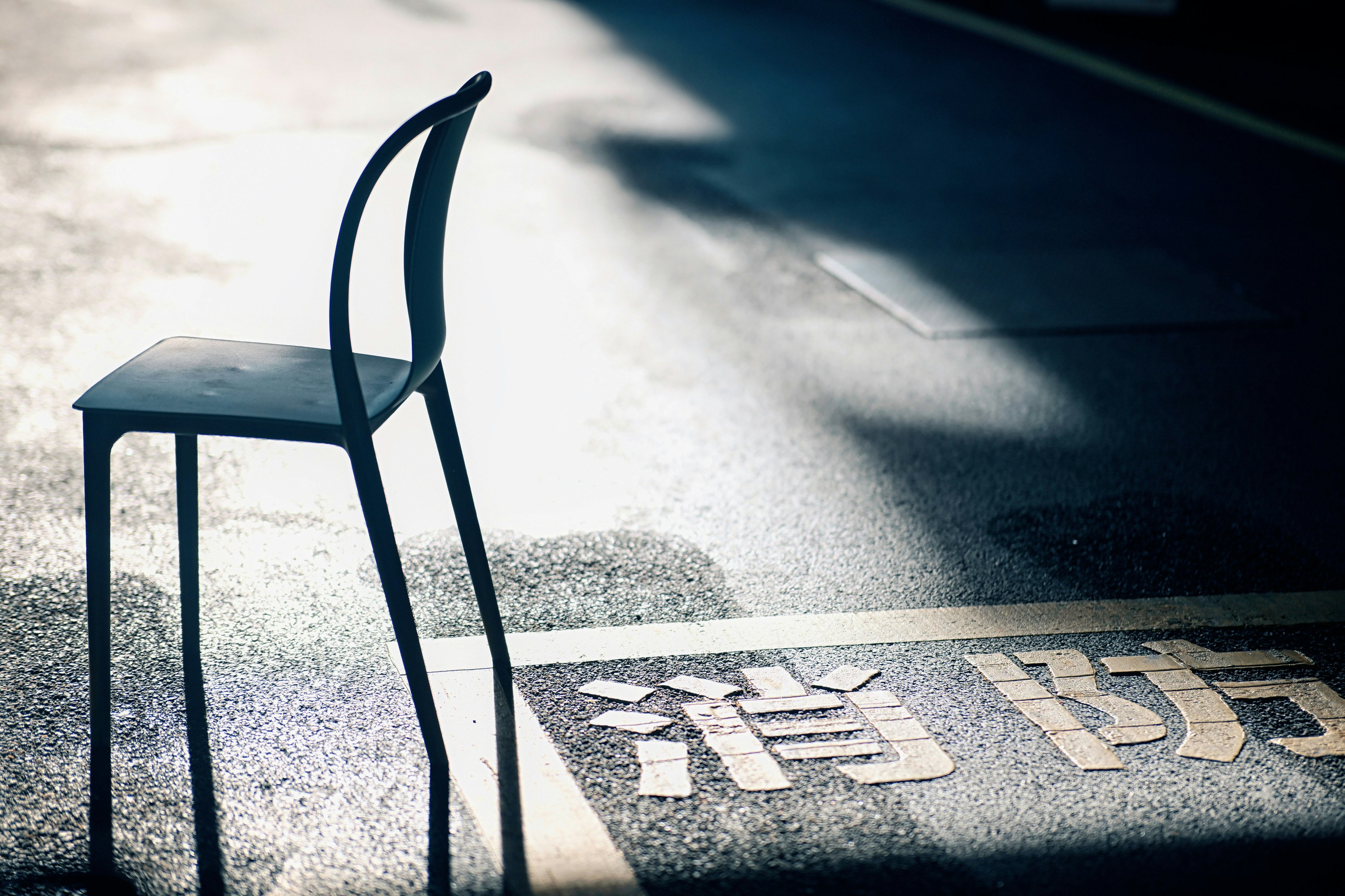 影のある椅子と路面の文字が見える歩道