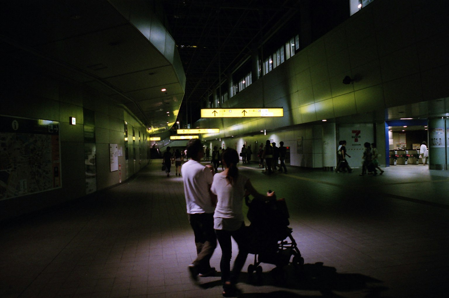 Silhouette d'un couple marchant avec une poussette dans un couloir faiblement éclairé