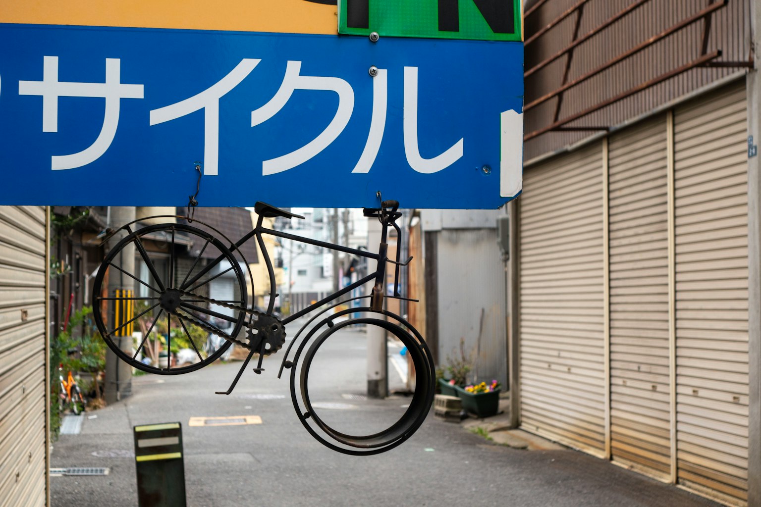 Bicycle sculpture hanging from a sign of a cycle shop