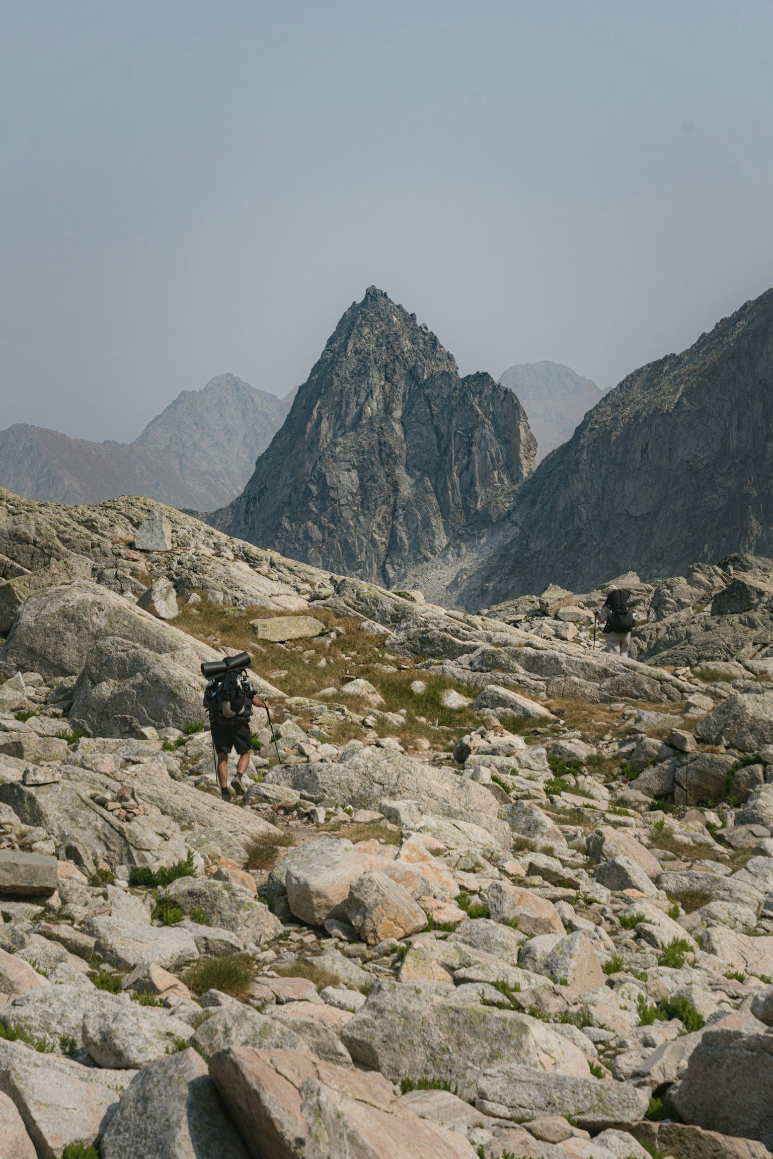 険しい山道を歩くハイカーと岩の多い風景