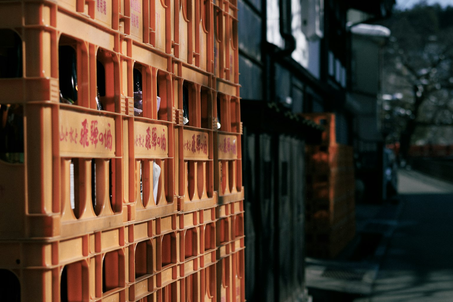 Orange plastic crates stacked along a street with blurred background