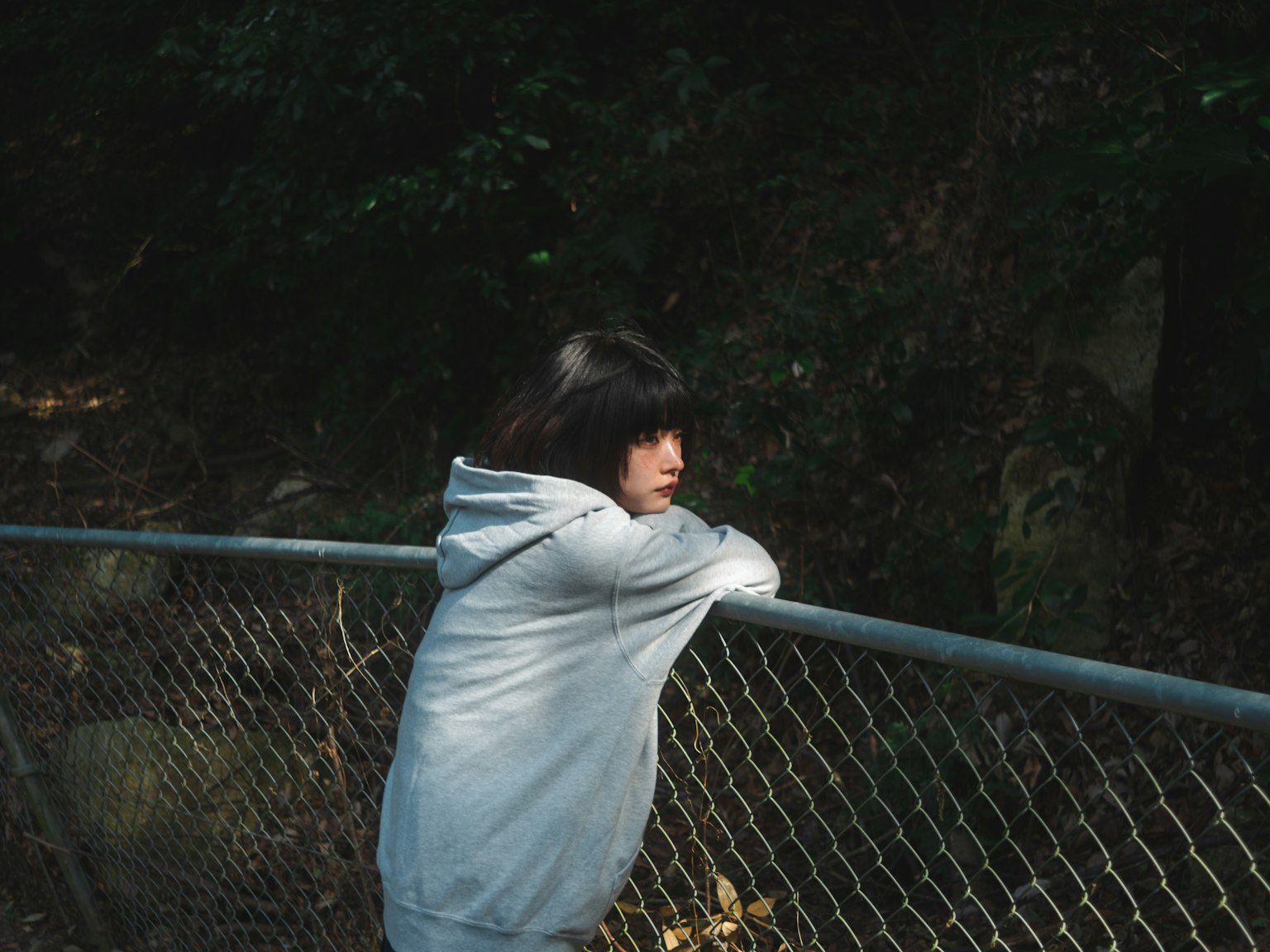 Girl leaning on a fence gazing into the forest