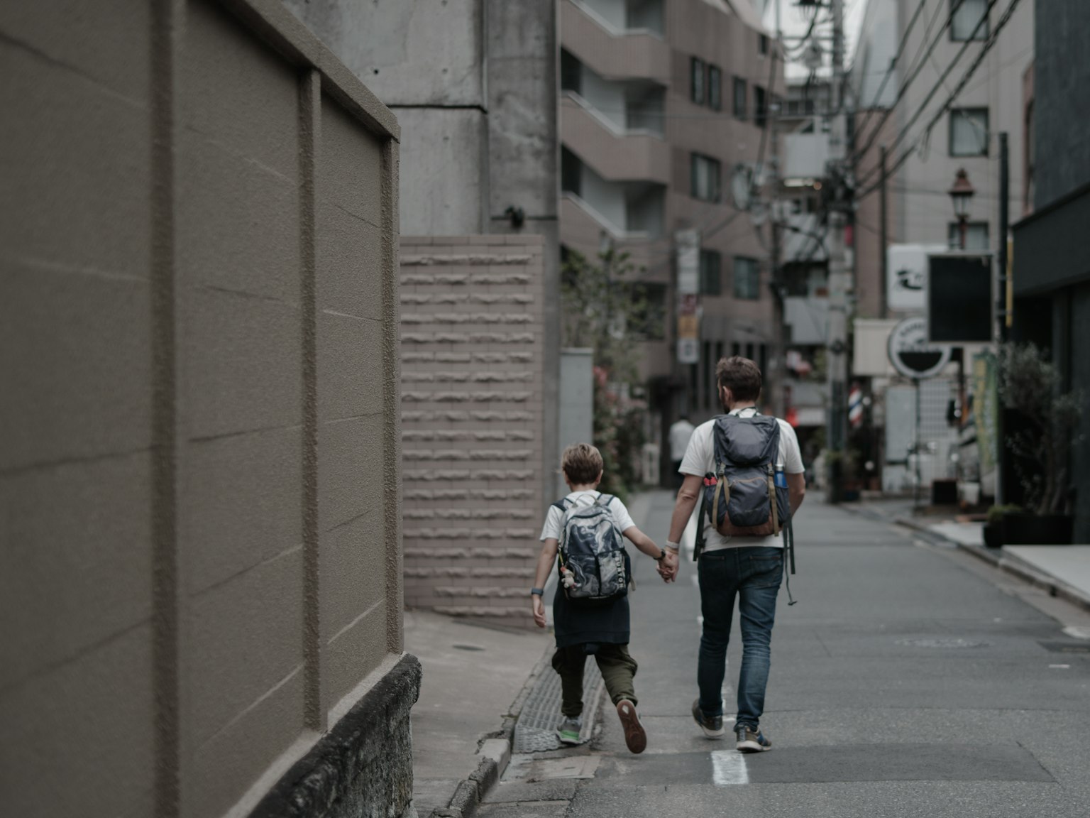 Un genitore e un bambino che camminano mano nella mano in una strada della città