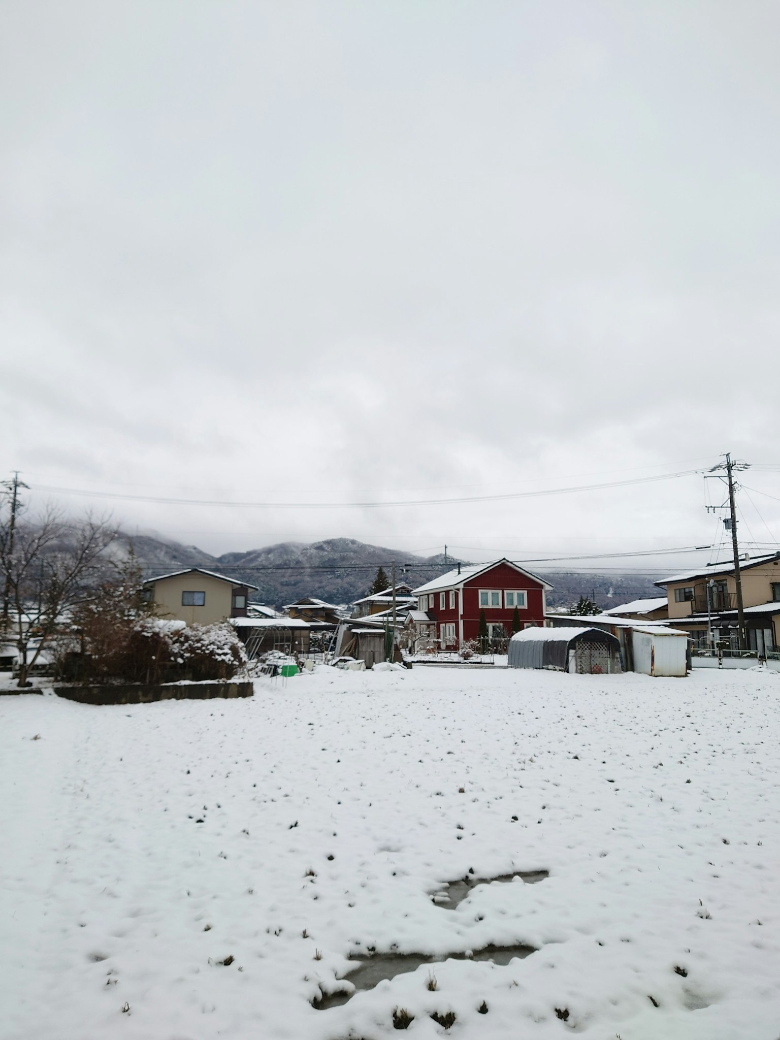 Ruhige Dorfansicht im Schnee mit einem roten Haus und verschneiten Bergen