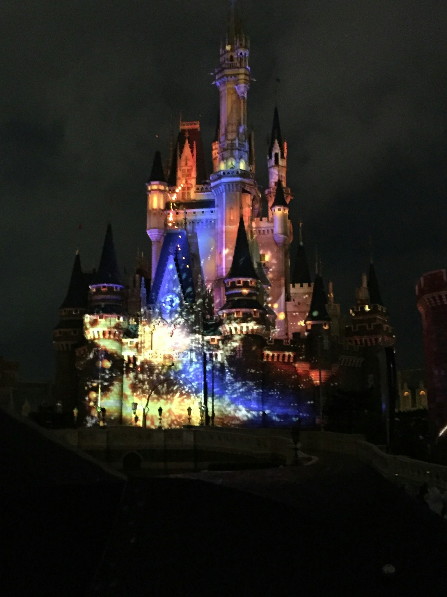 Castillo de Disney iluminado por la noche con proyecciones coloridas