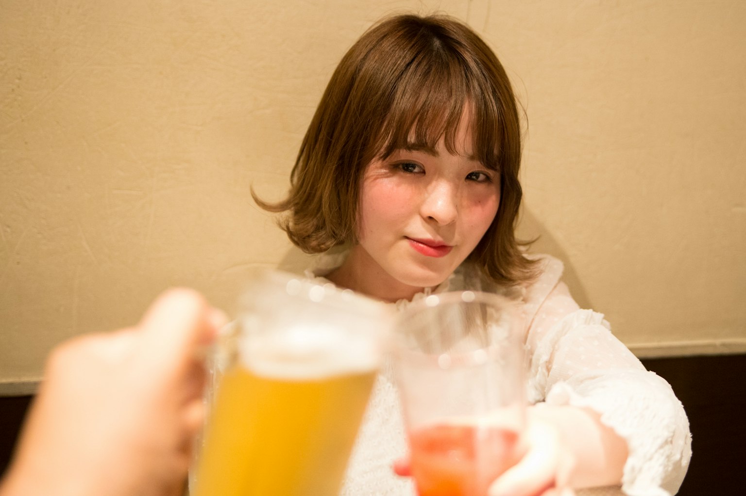 Una mujer sonriente sosteniendo un cóctel y una cerveza