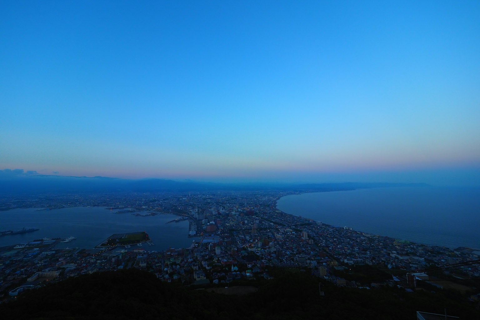 วิวพาโนรามาของเมืองชายฝั่งในยามค่ำคืนกับท้องฟ้าสีฟ้า