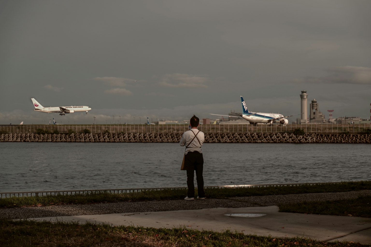 Persona observando aviones cerca de un aeropuerto junto al agua
