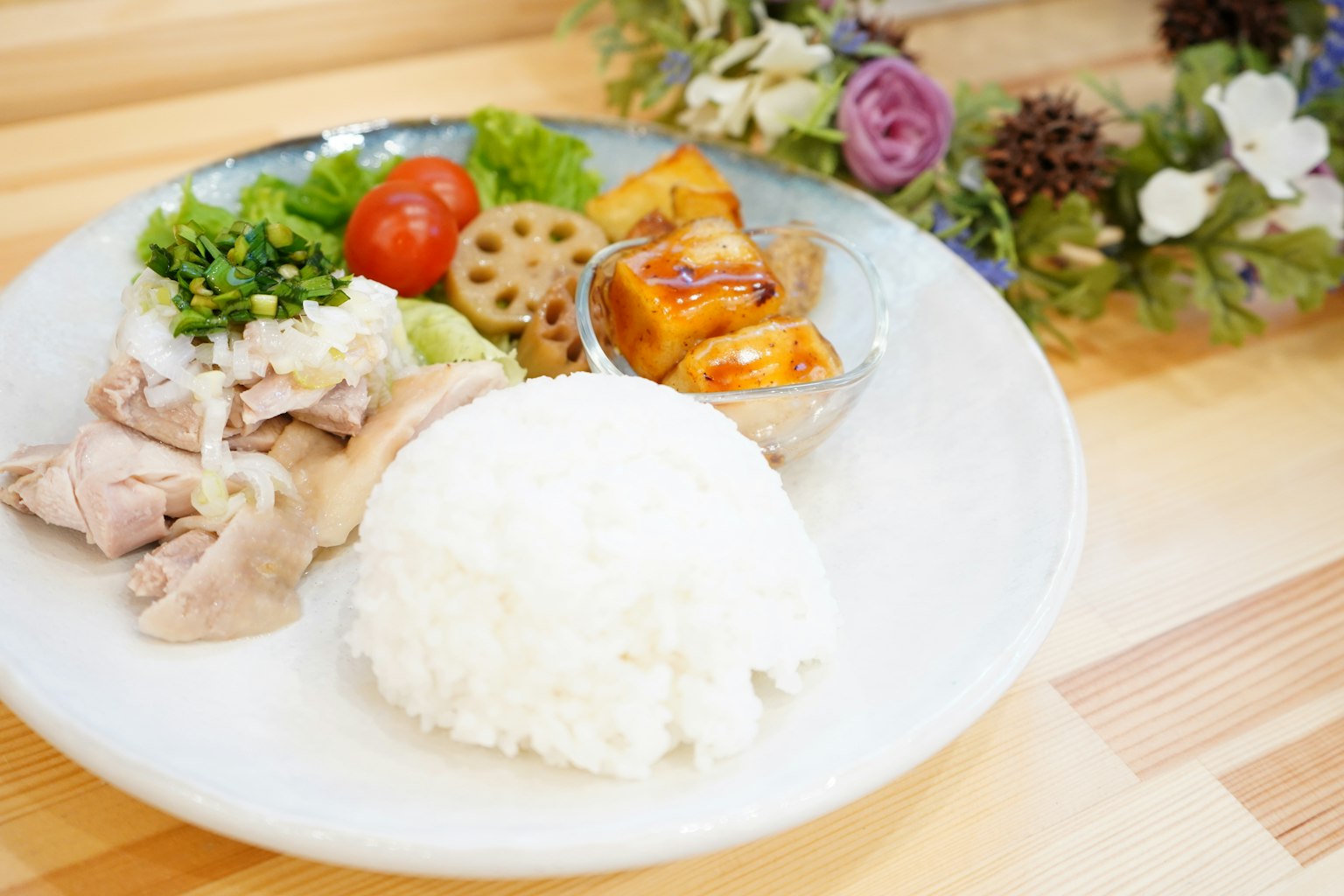 盘子里有蒸米饭、鸡肉和新鲜蔬菜以及配菜