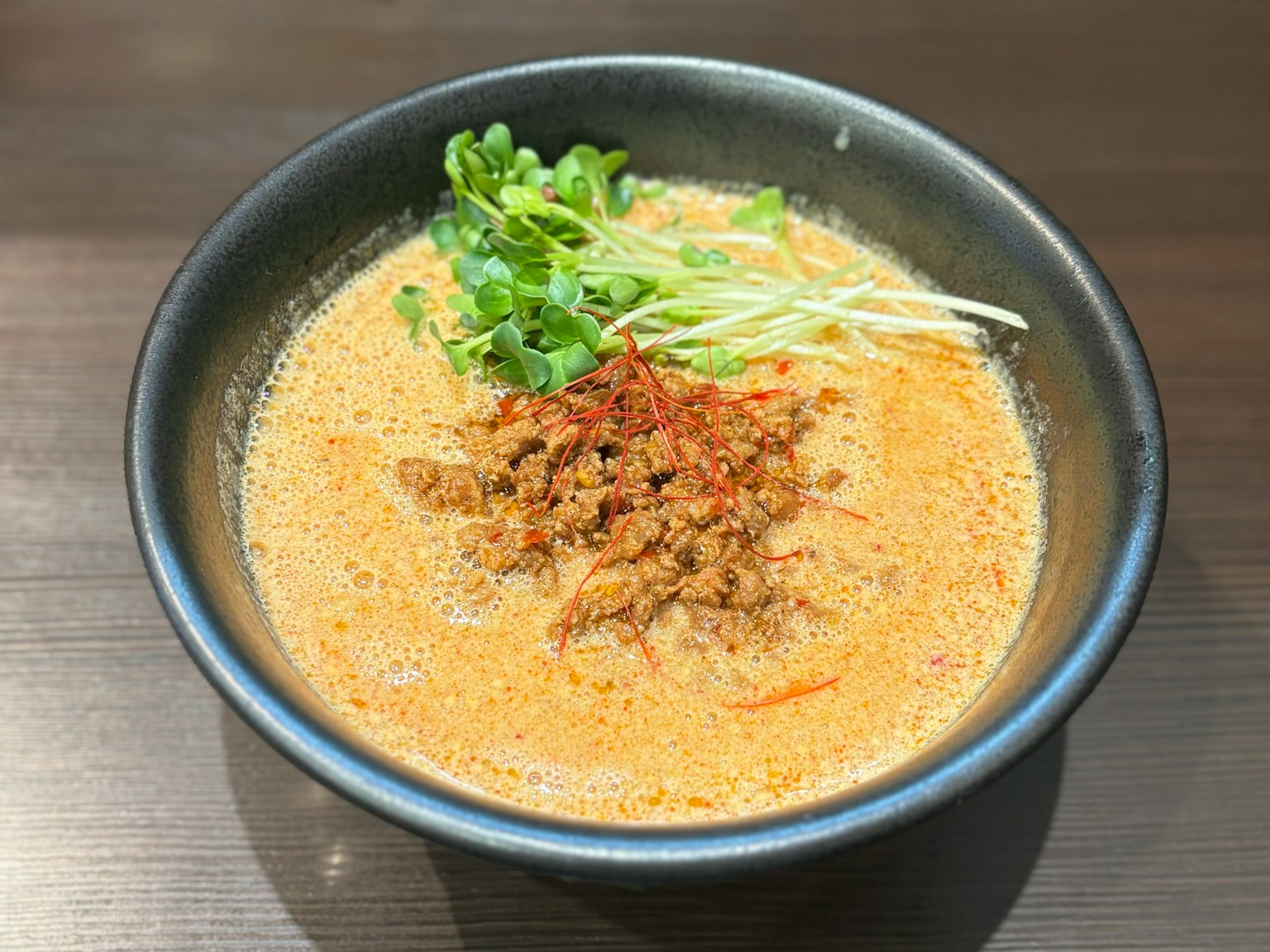 奶油湯拉麵，上面放有剁碎的肉和綠色香草
