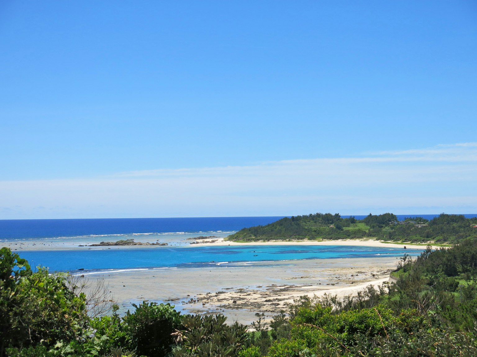 Schöner Blick auf das blaue Meer und den weißen Sandstrand mit grünen Bäumen