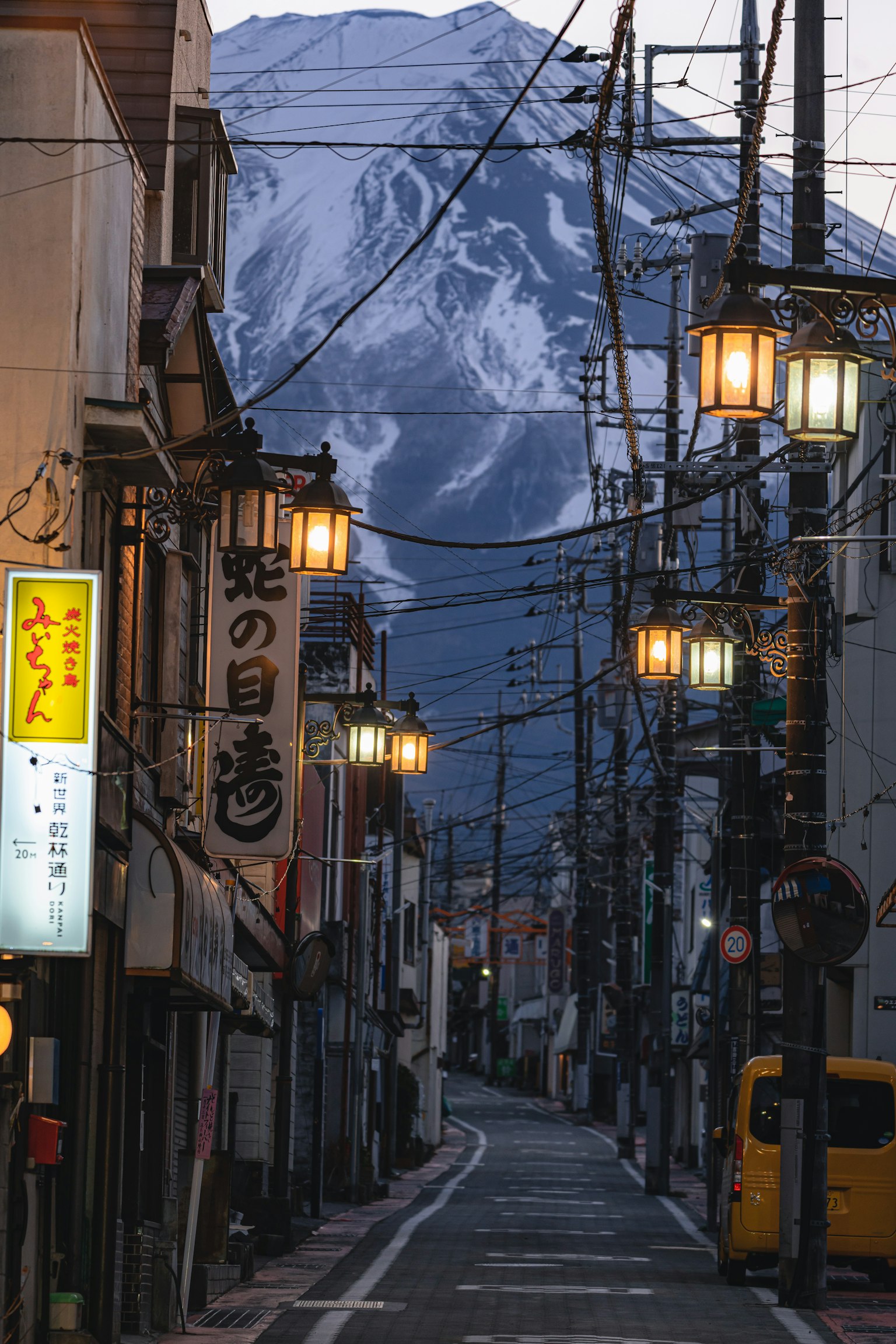 Quiet street scene at night with mountains in the background Street lights illuminating traditional storefronts