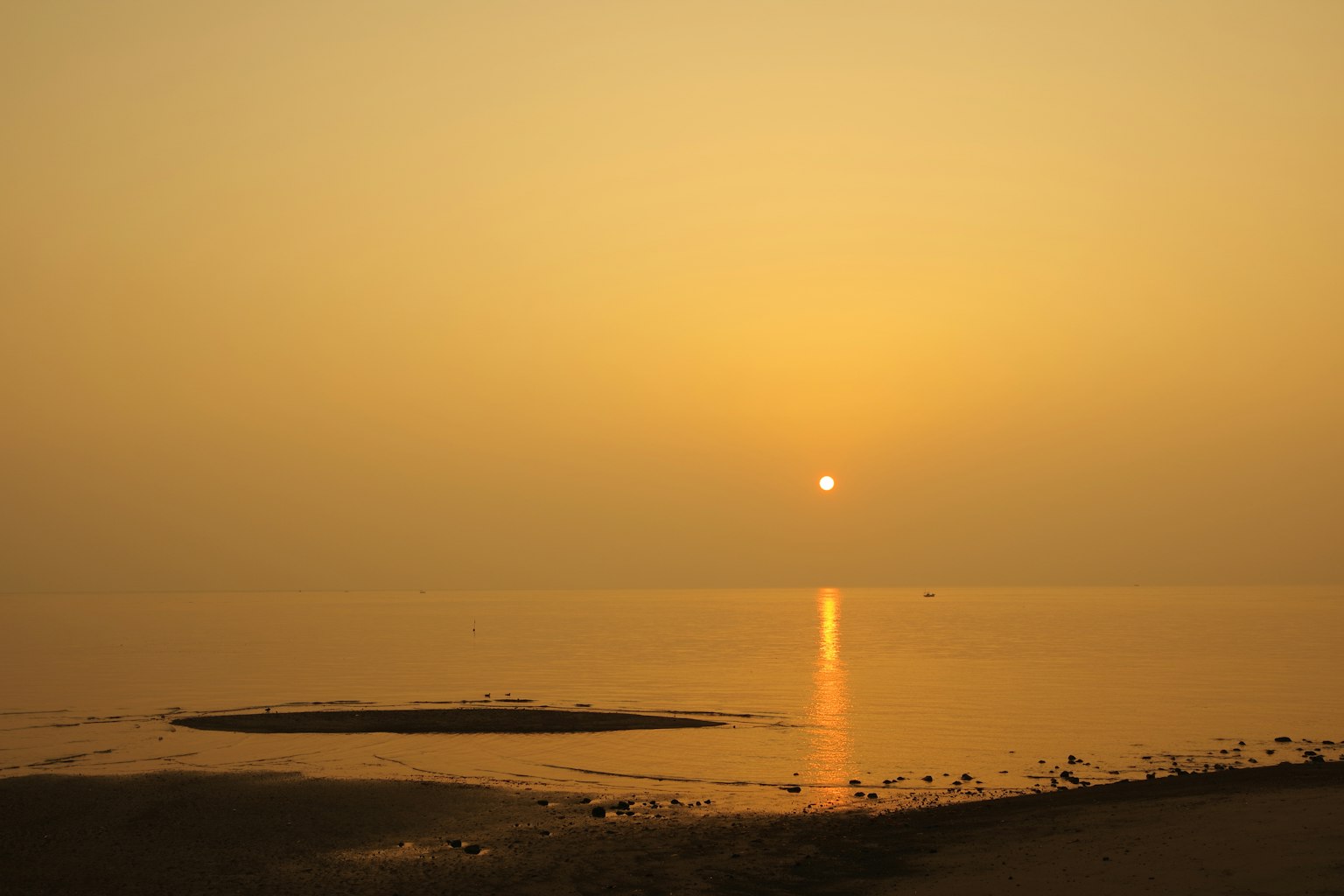 Calm sea with sunset reflecting on the water and an orange sky