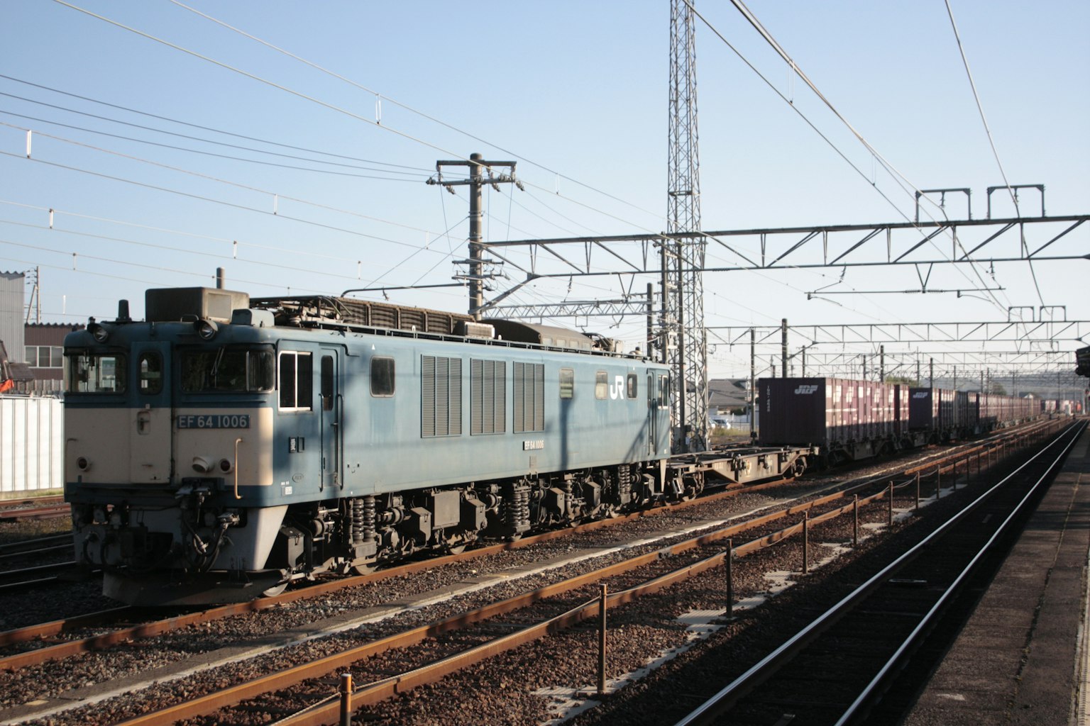 Blue locomotive pulling freight train at a railway station