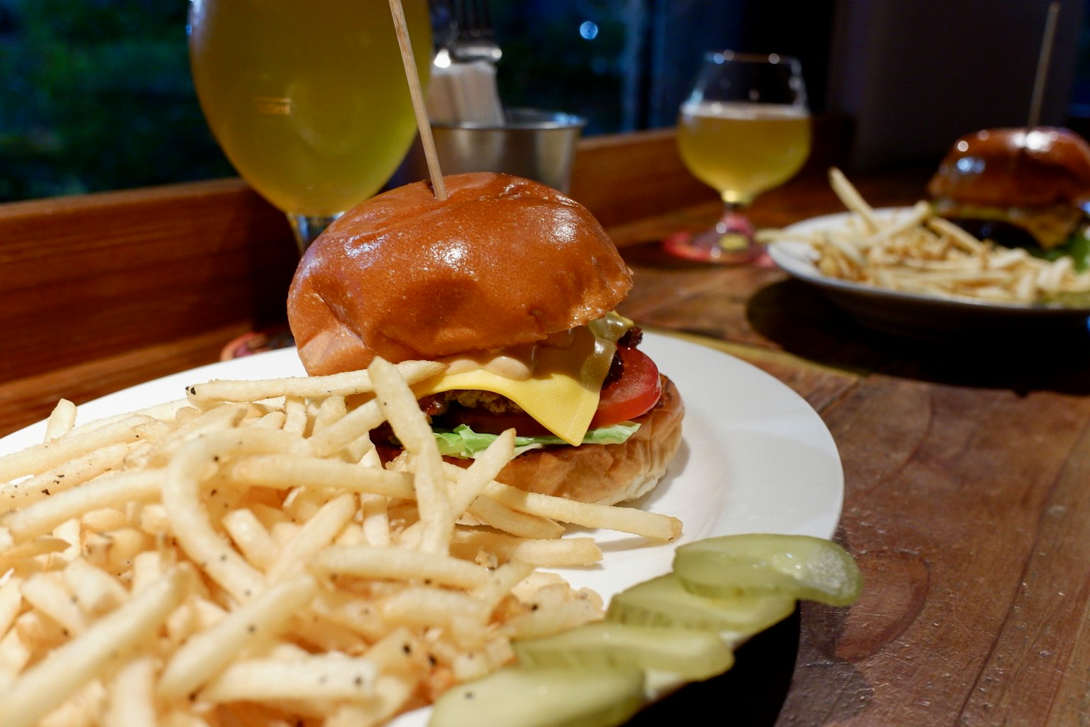 Hamburger au fromage délicieux avec des frites et des cornichons sur une table en bois
