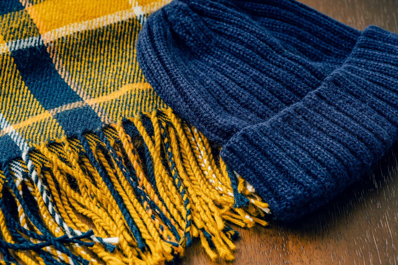 Ein karierter Schal und eine marineblaue Strickmütze liegen zusammen