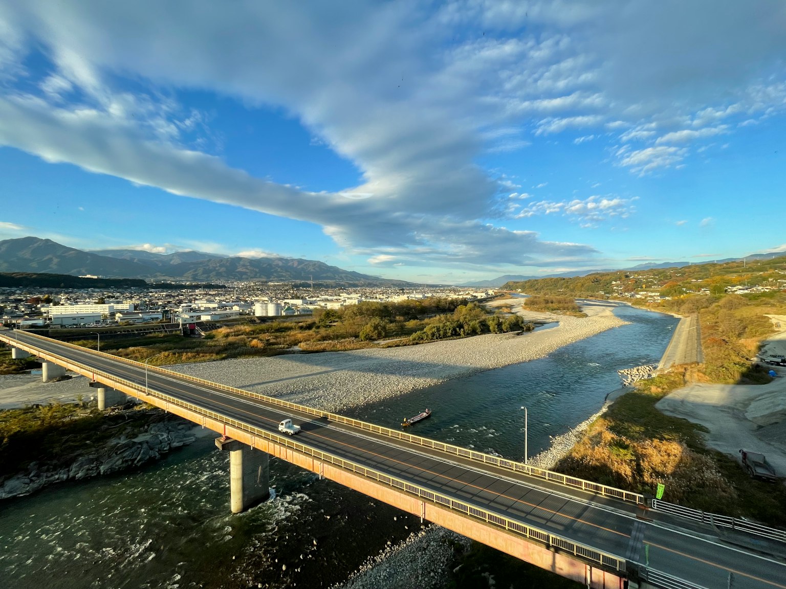 Bridge over a river with a clear sky and scattered clouds