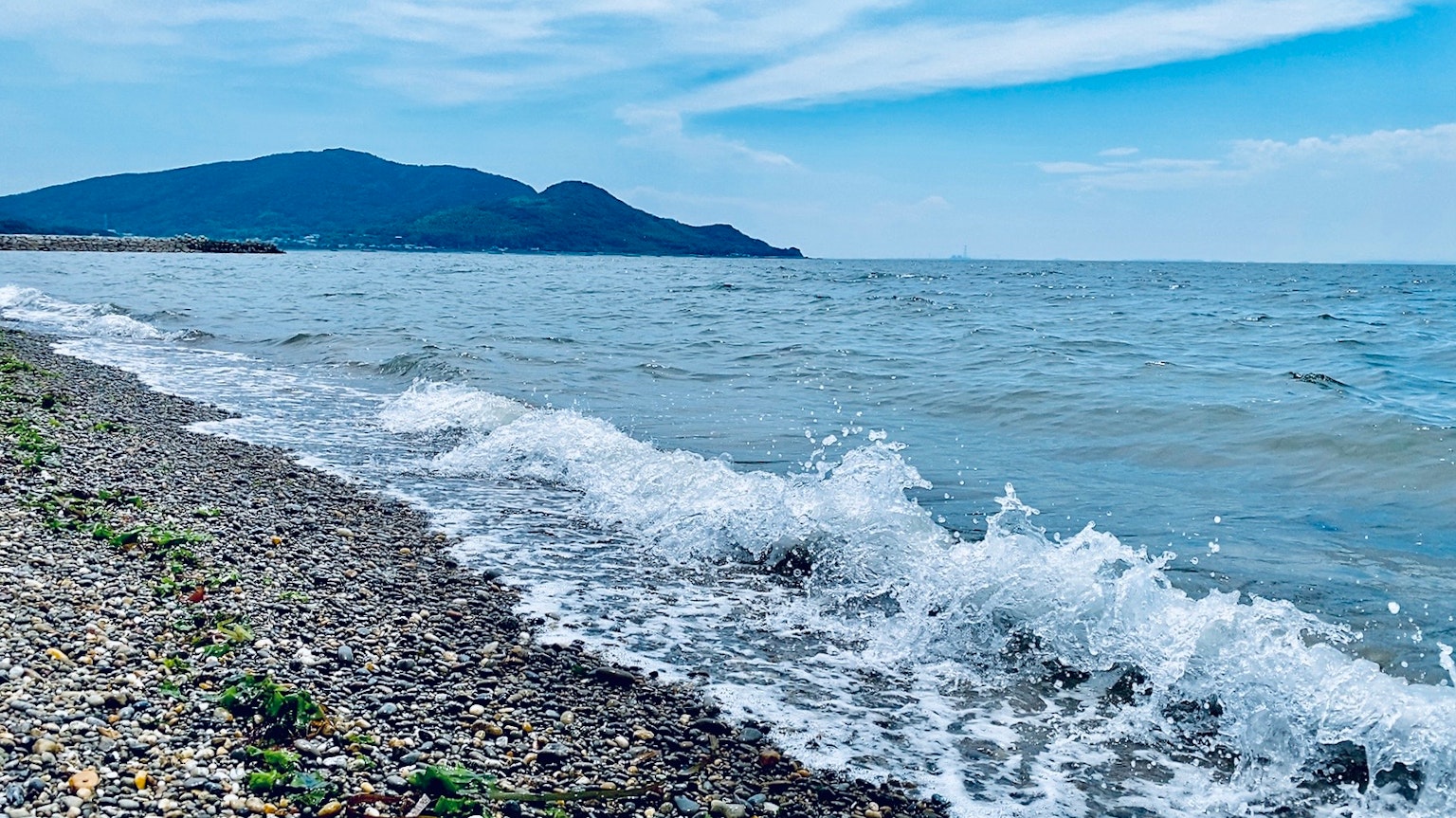 Beruhigte Ozeanwellen, die gegen einen Kiesstrand schlagen