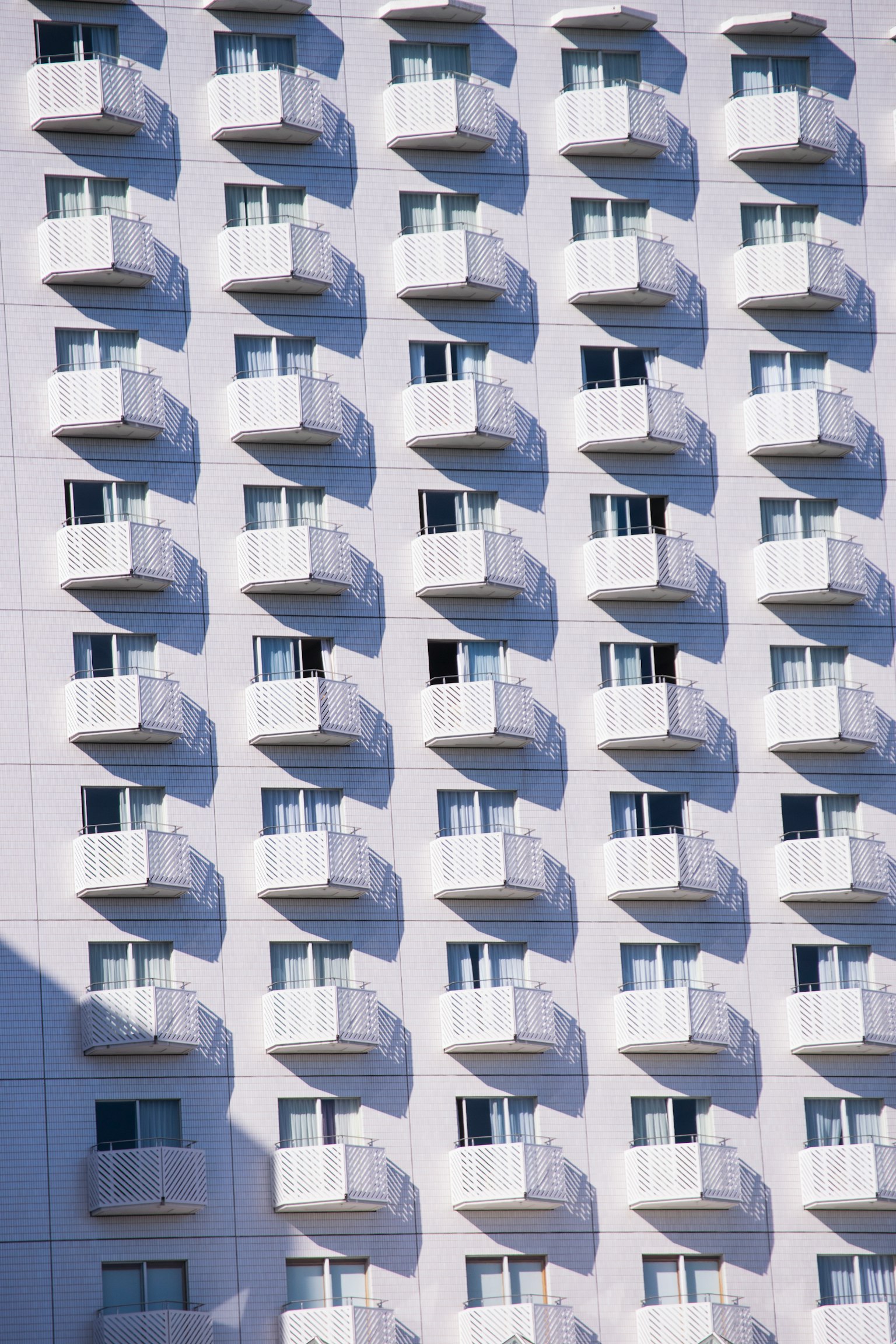 Una pared de un edificio blanco con numerosos balcones y ventanas