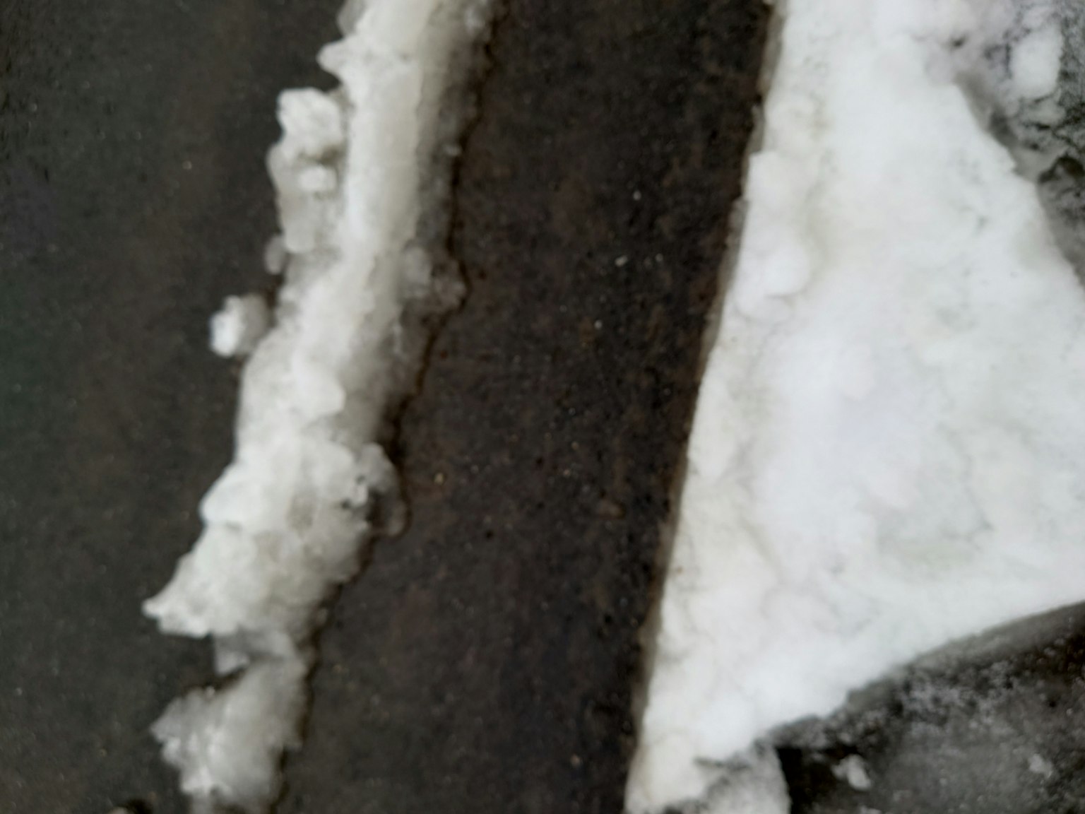Una sezione di una strada coperta di neve e asfalto scuro